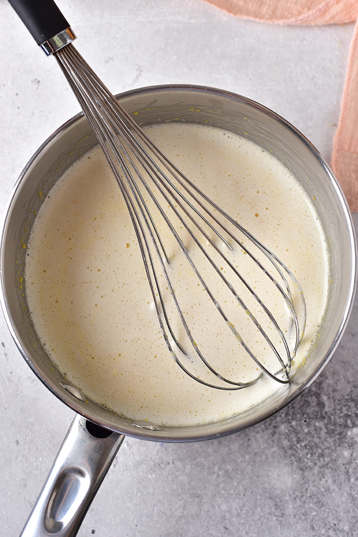 Carefully place a bit of the hot milk into the egg yolk mixture, and whisk quickly to combine.