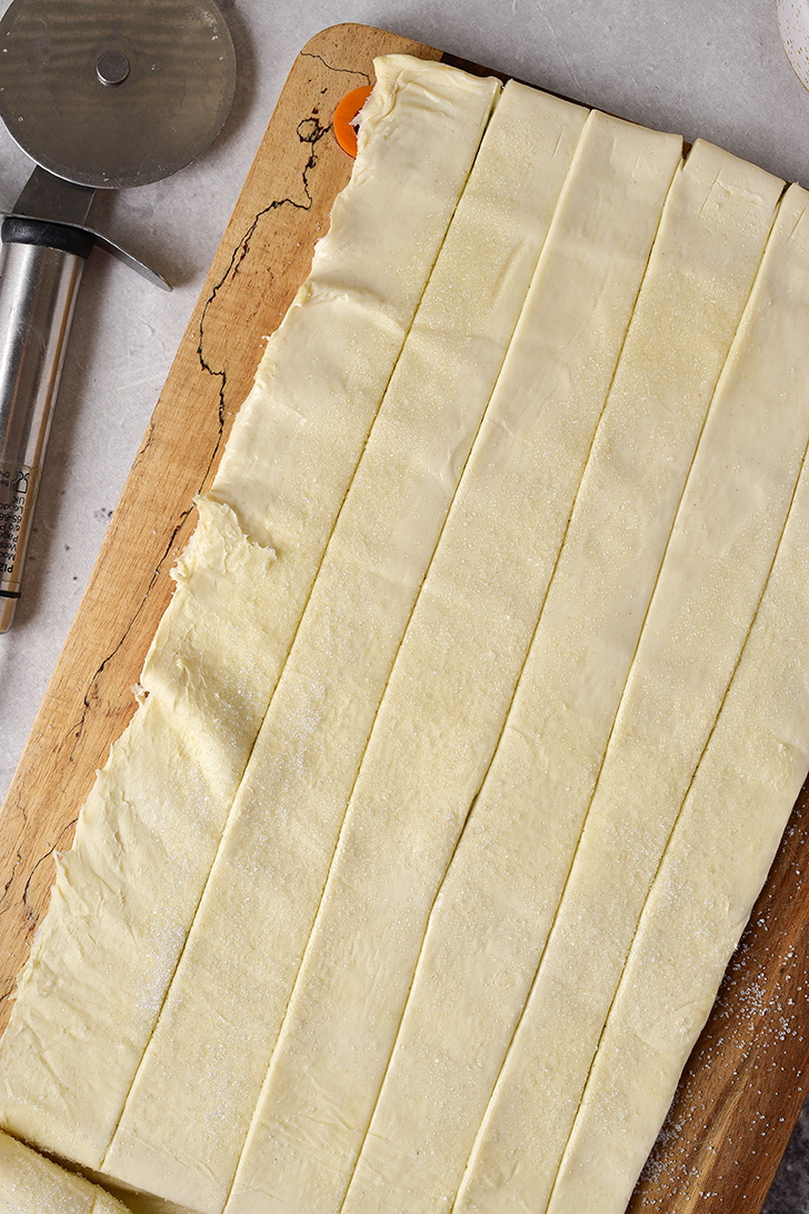 Slice the puff pastry sheet into 12 thin strips that are 1 inch wide.