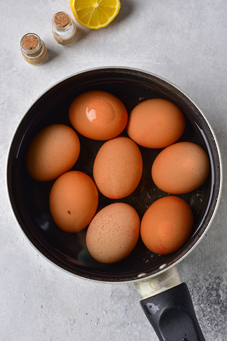 Cover the eggs with water in a pot, and bring them to a boil. Once boiling, turn the heat off, cover the pot, and allow it to sit for 15-20 minutes. Immediately add the eggs to an ice water bath, and then peel. 
