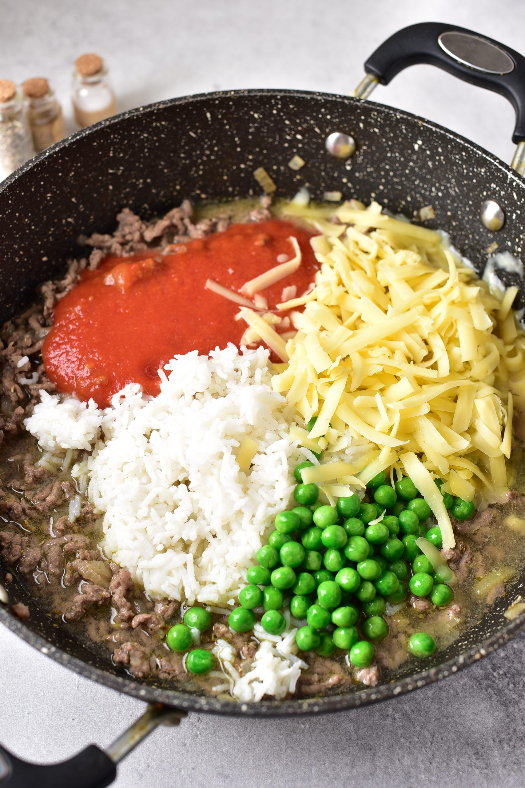 Mix in the tomato sauce, rice, peas, broth, and one cup of cheese. Simmer the mixture until the cheese has melted. 