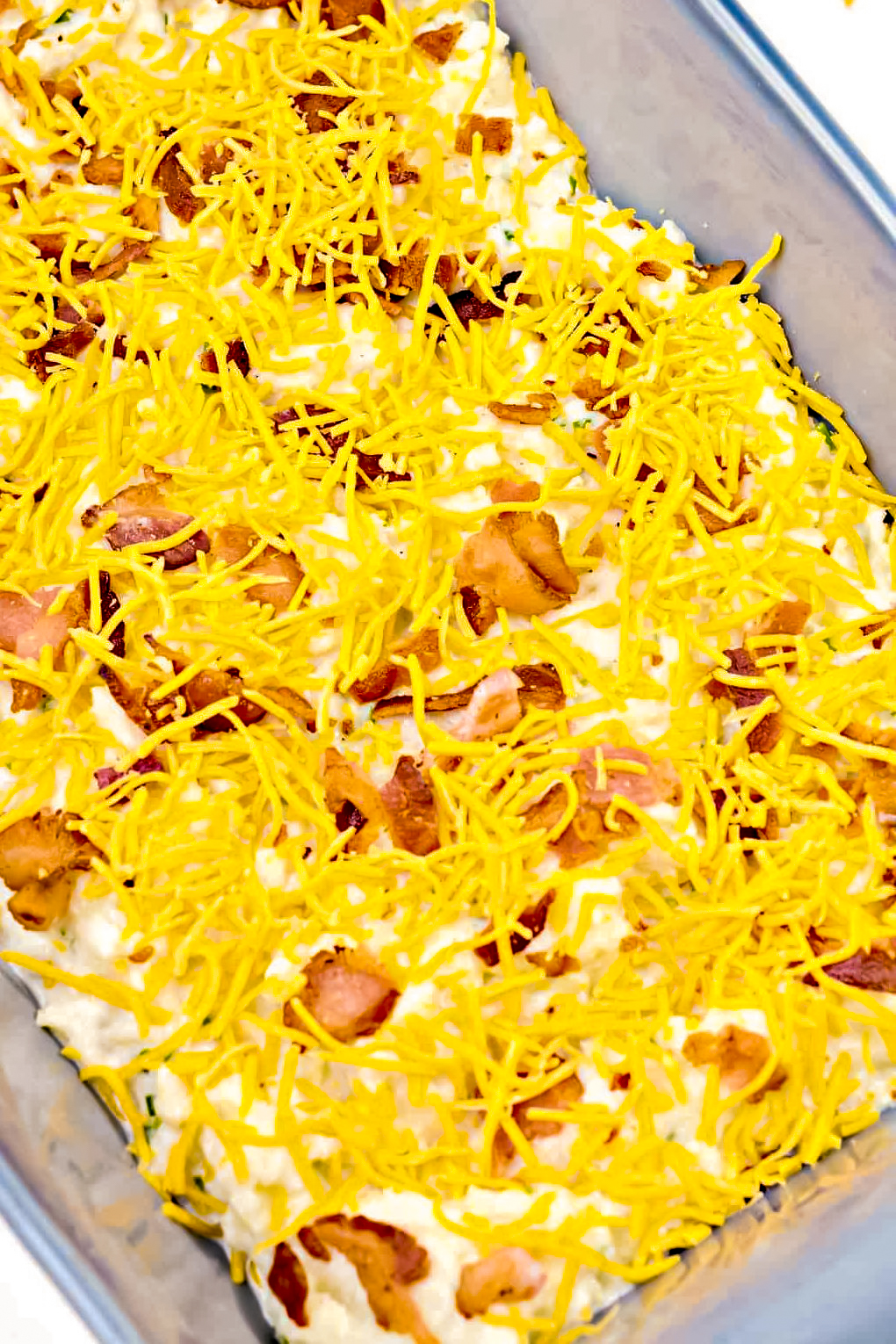 Top the cauliflower with the crumbled bacon and shredded cheese.