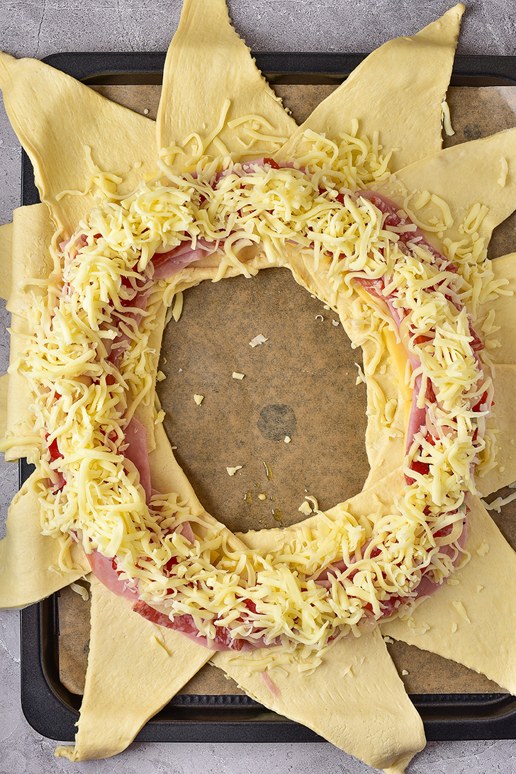 On top of the cheese, layer the ham, then the salami, pepper mixture, and mozzarella cheese.