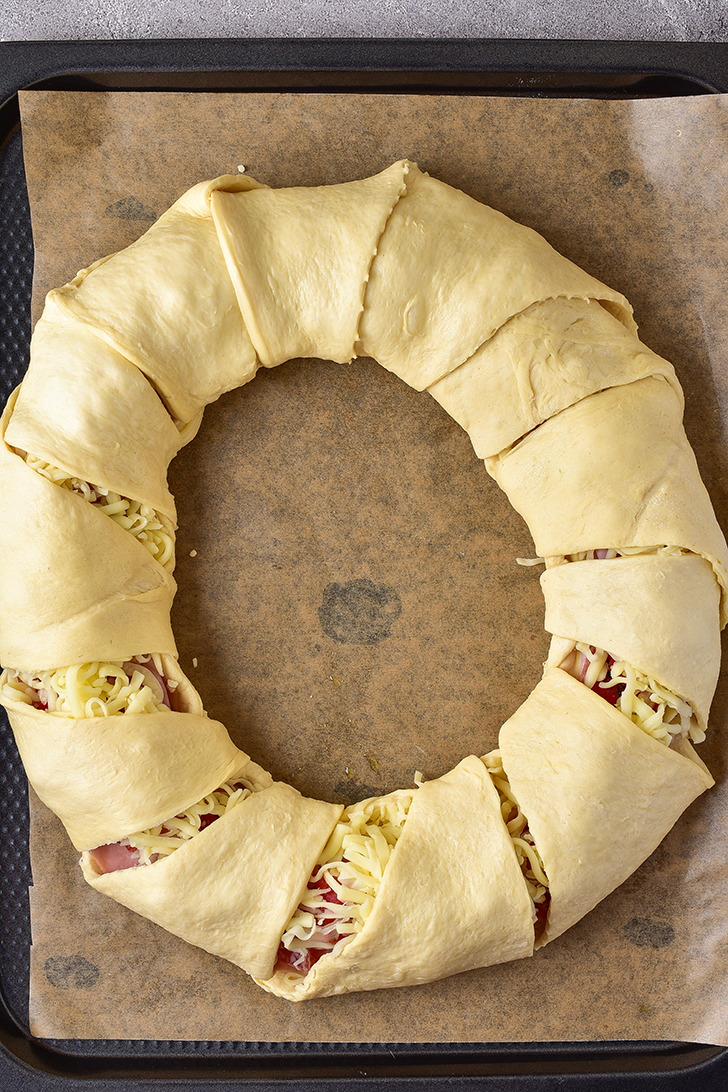 Fold the pointed ends of the dough over the filling, and tuck it closed under the inside of the circle.