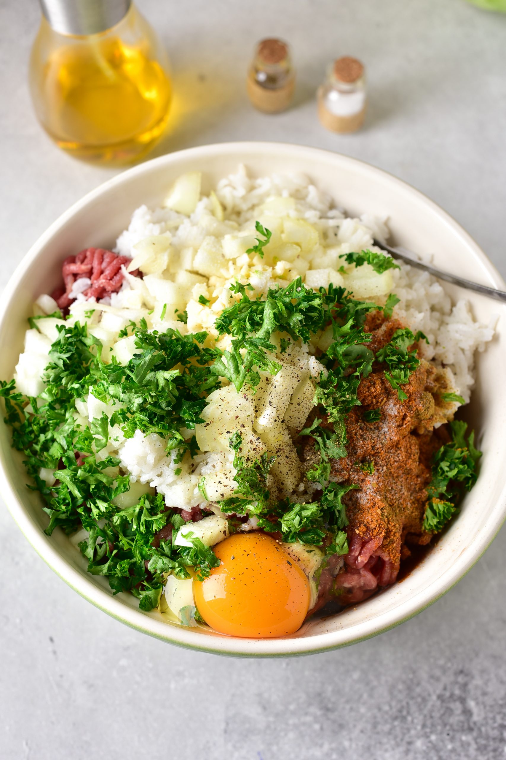 In a bowl, stir together the ground beef, eggs, cumin, Italian seasoning, white rice, ½ cup onion, parsley, and salt and pepper to taste. 