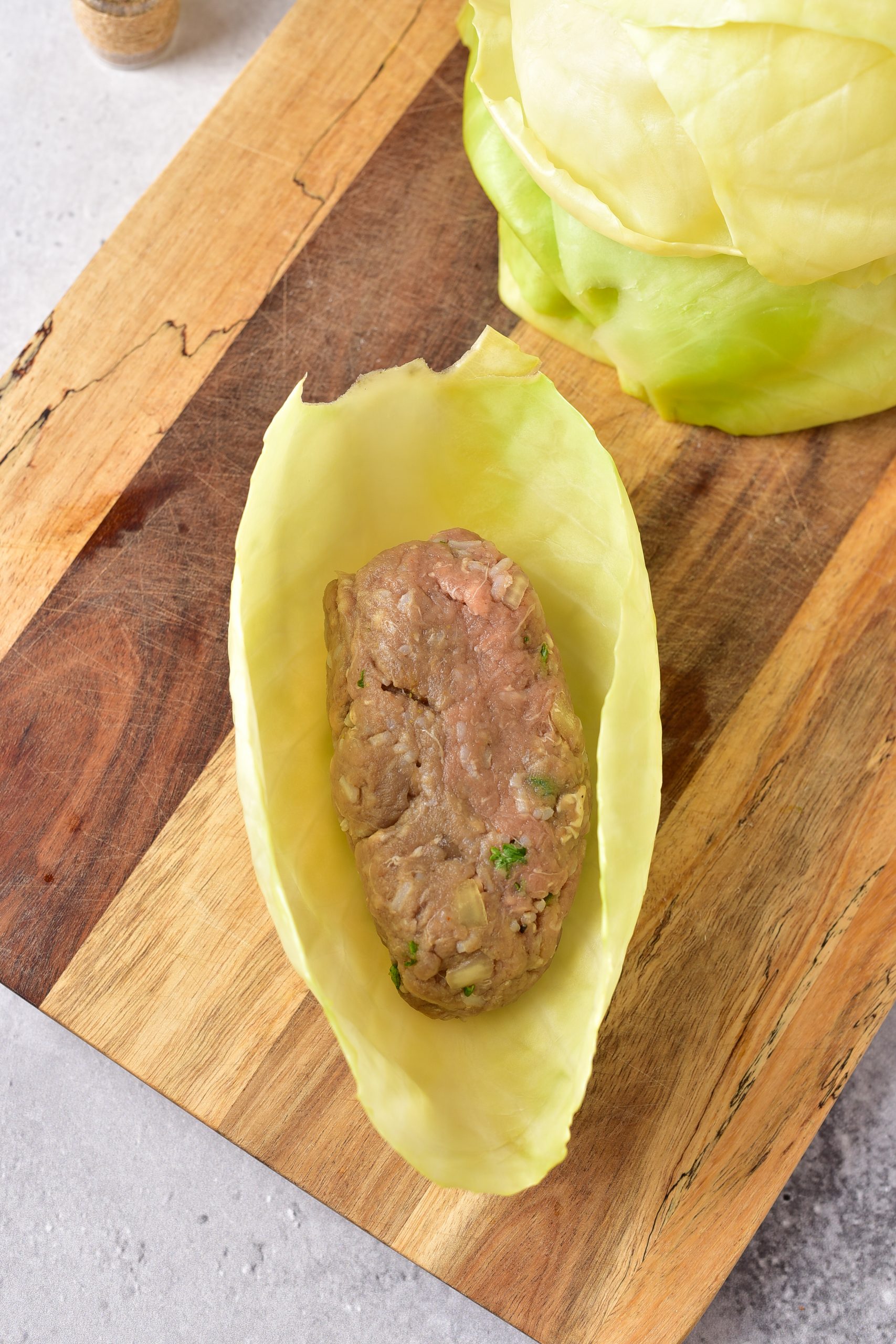 Form the meat mixture into 12 evenly sized balls, and place each one into the center of a cabbage leaf. 