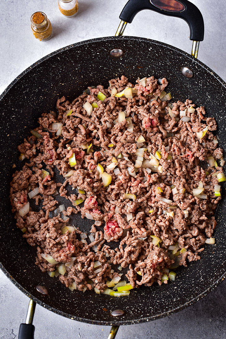 Place the ground beef and onion into a skillet over medium-high heat, and saute until the meat is browned and the onions have softened. Drain the extra fat.