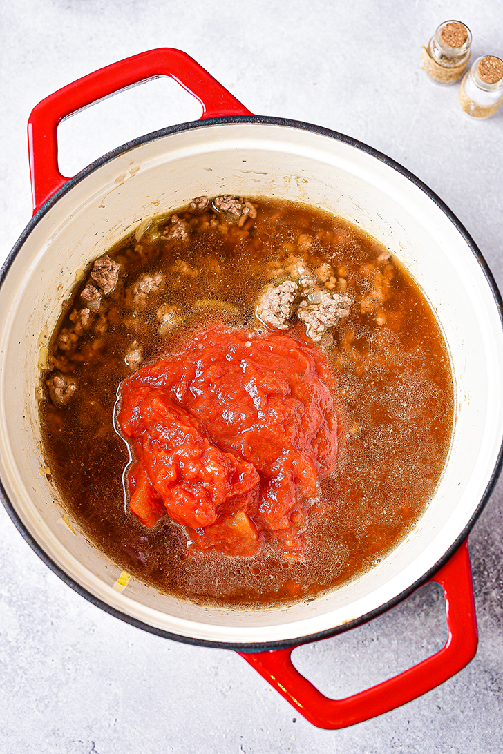 Mix in salt, pepper, stewed tomatoes, diced tomatoes, and beef broth. 