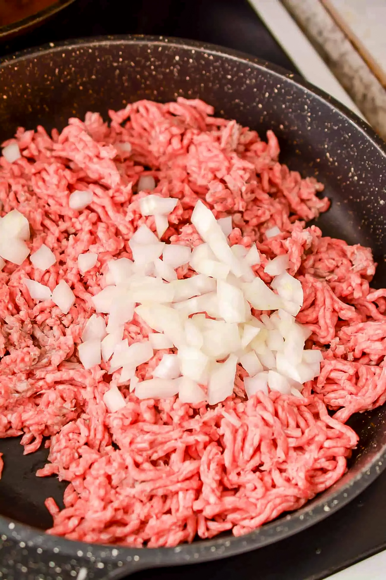 While the spaghetti is cooking, saute the meat and onion in a skillet over medium-high heat until the meat is browned and the onions are softened.