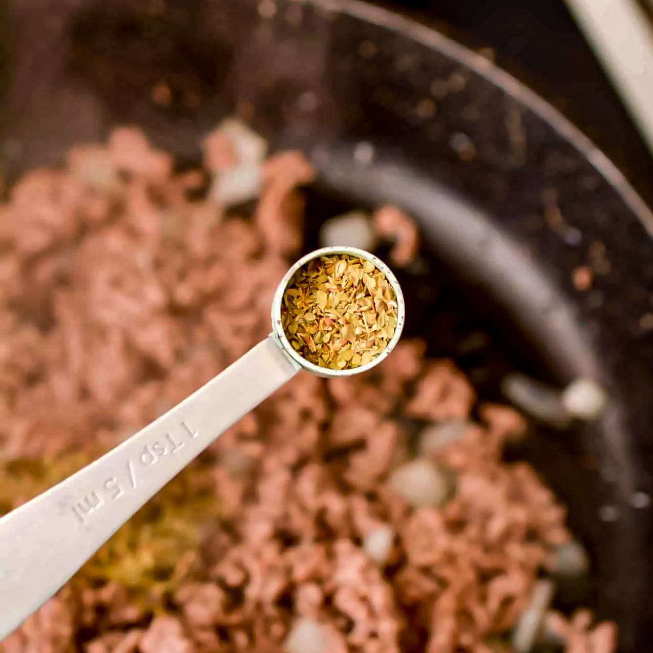 Stir oregano, basil, salt, and pepper to taste into the meat mixture.
