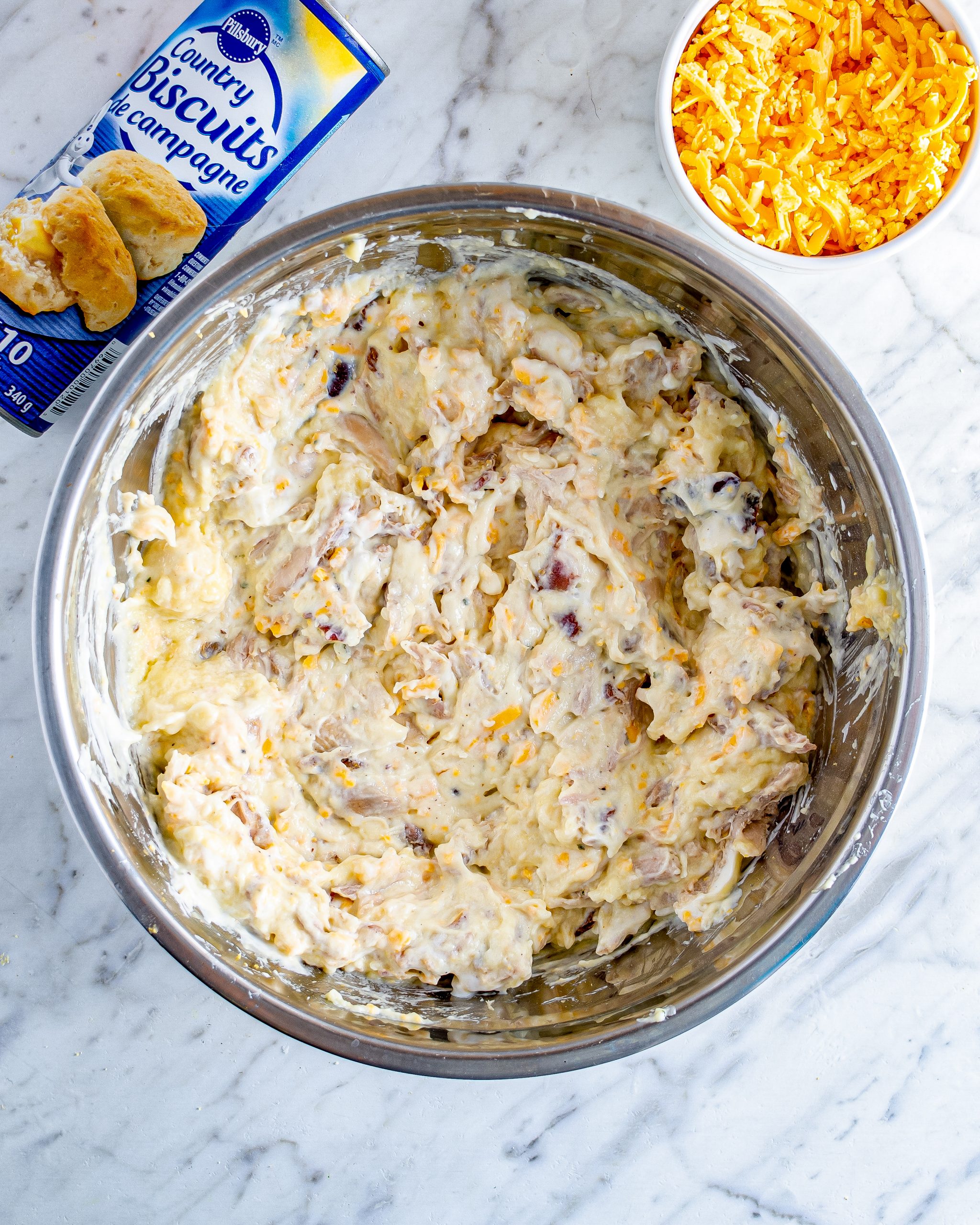In a bowl, mix together the sour cream, soups, chicken, Ranch seasoning, 1 cup of cheddar cheese, and bacon.