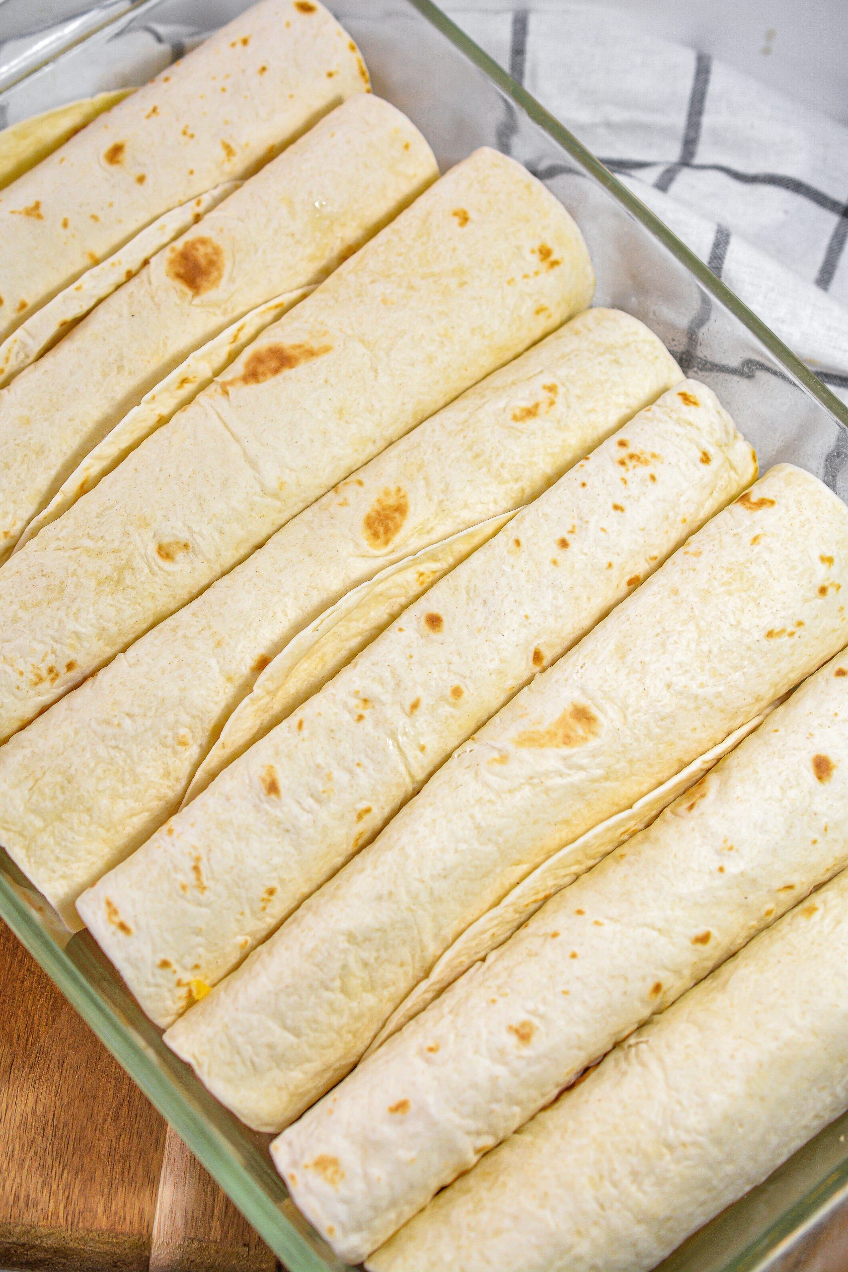 Fill the tortillas with the chicken mixture, and fold them closed. Line the filled tortillas in a 9x13 greased baking dish
