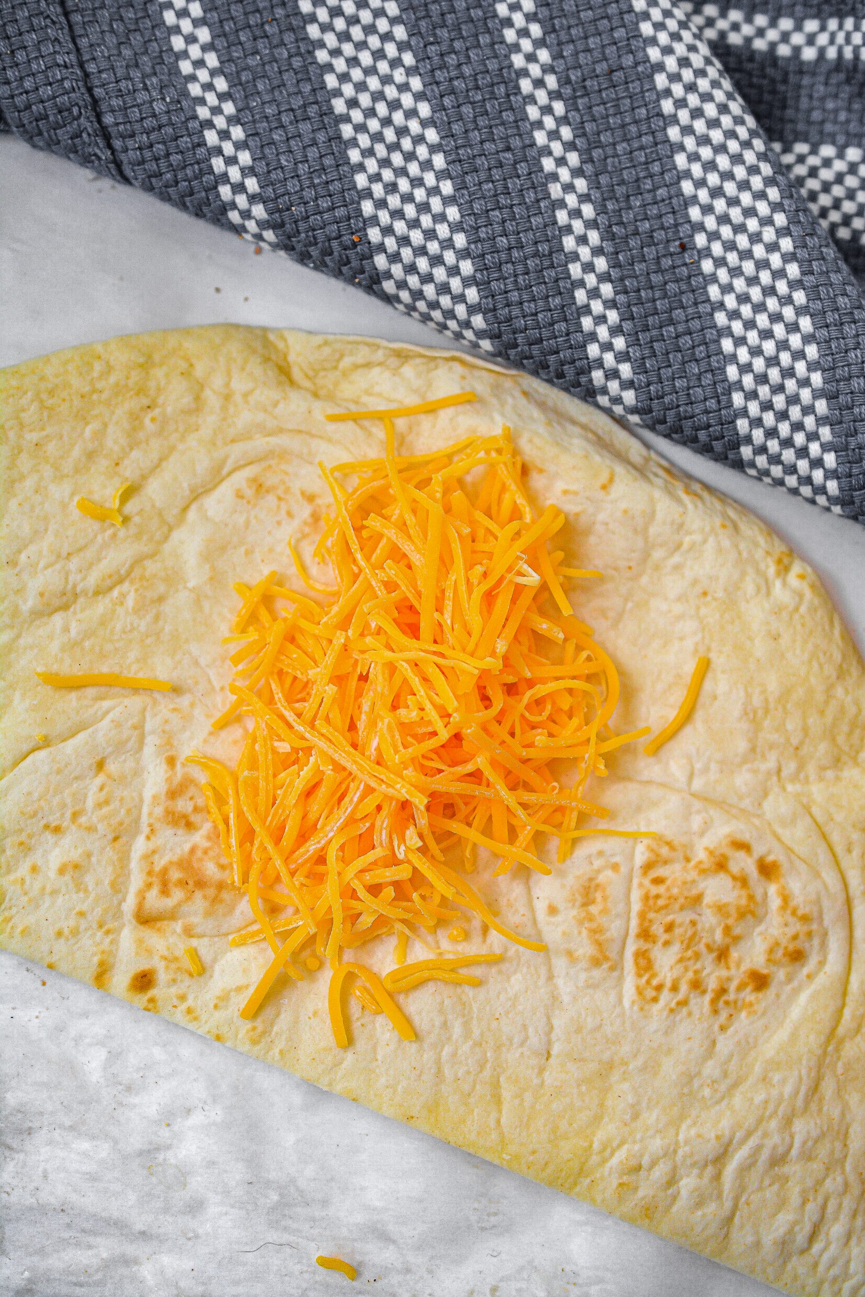 Place a small amount of cheddar cheese in the center of each half of the tortilla and top with a tablespoon or two of the filling.