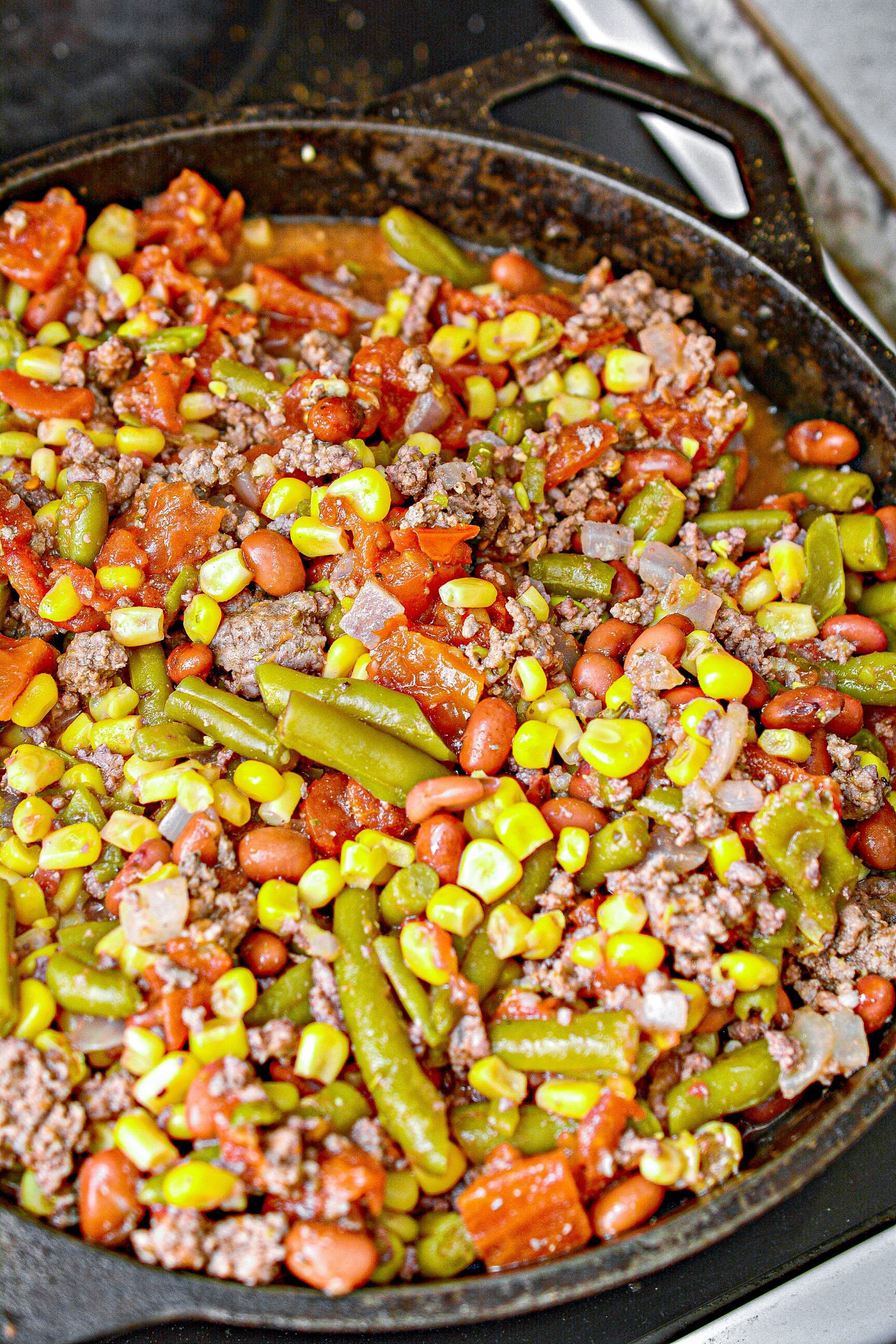 Pour the corn, green beans, red beans, stewed tomatoes, and diced tomatoes into the pot or skillet, and stir to combine completely.