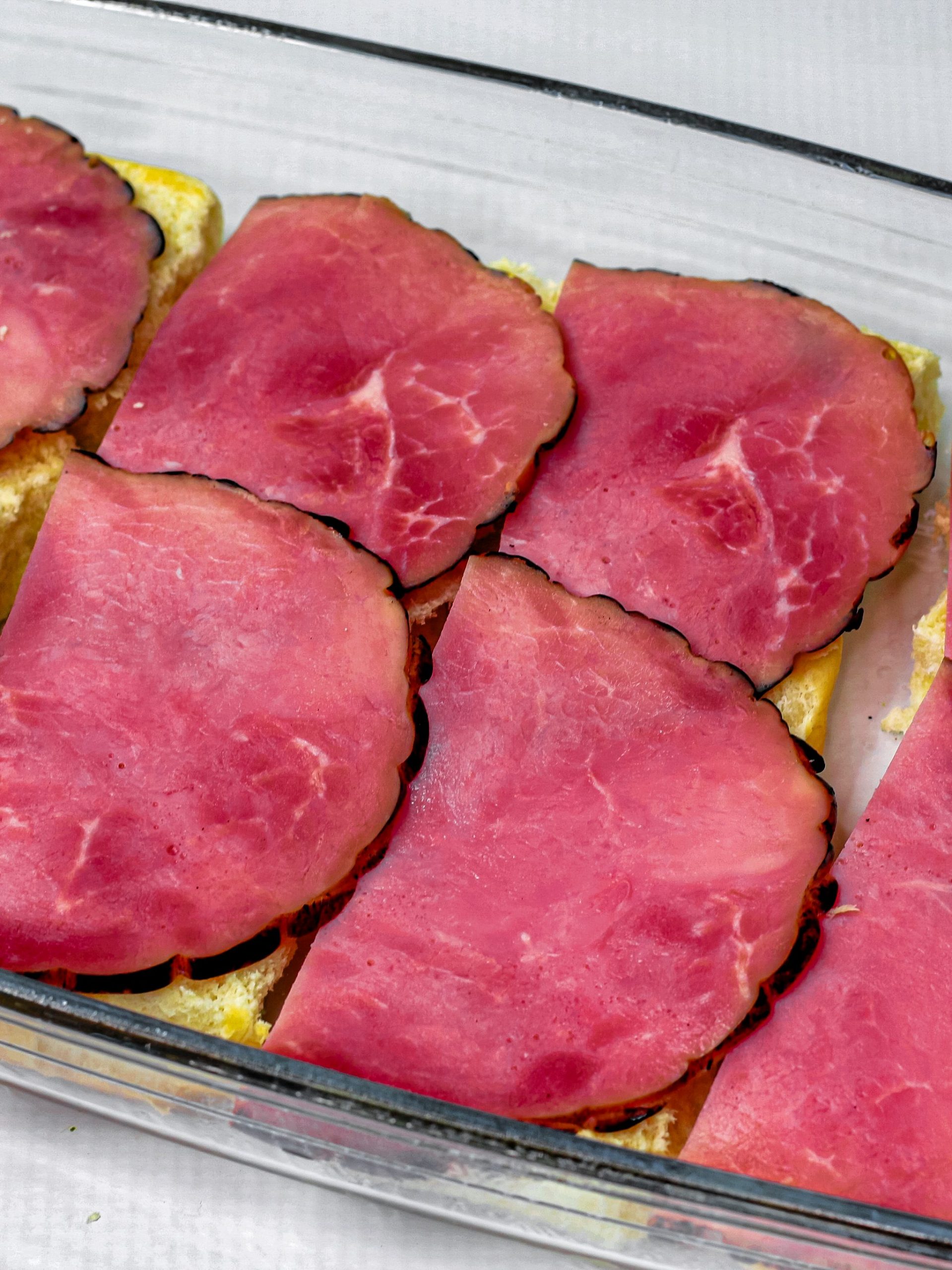 Place the ham on top of the Hawaiian roll bottoms.