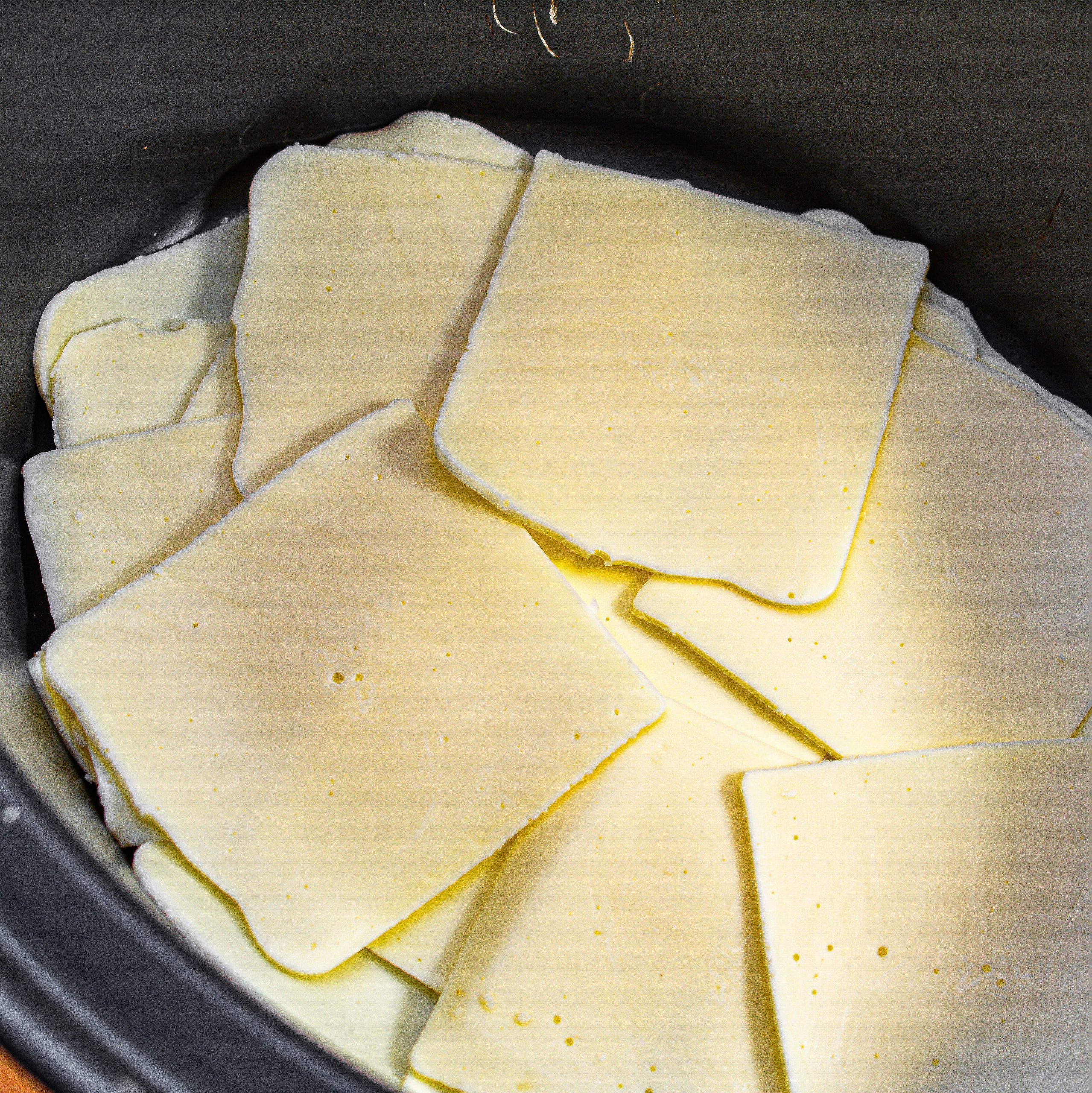 Layer the cheese slices in the bottom of a slow cooker.