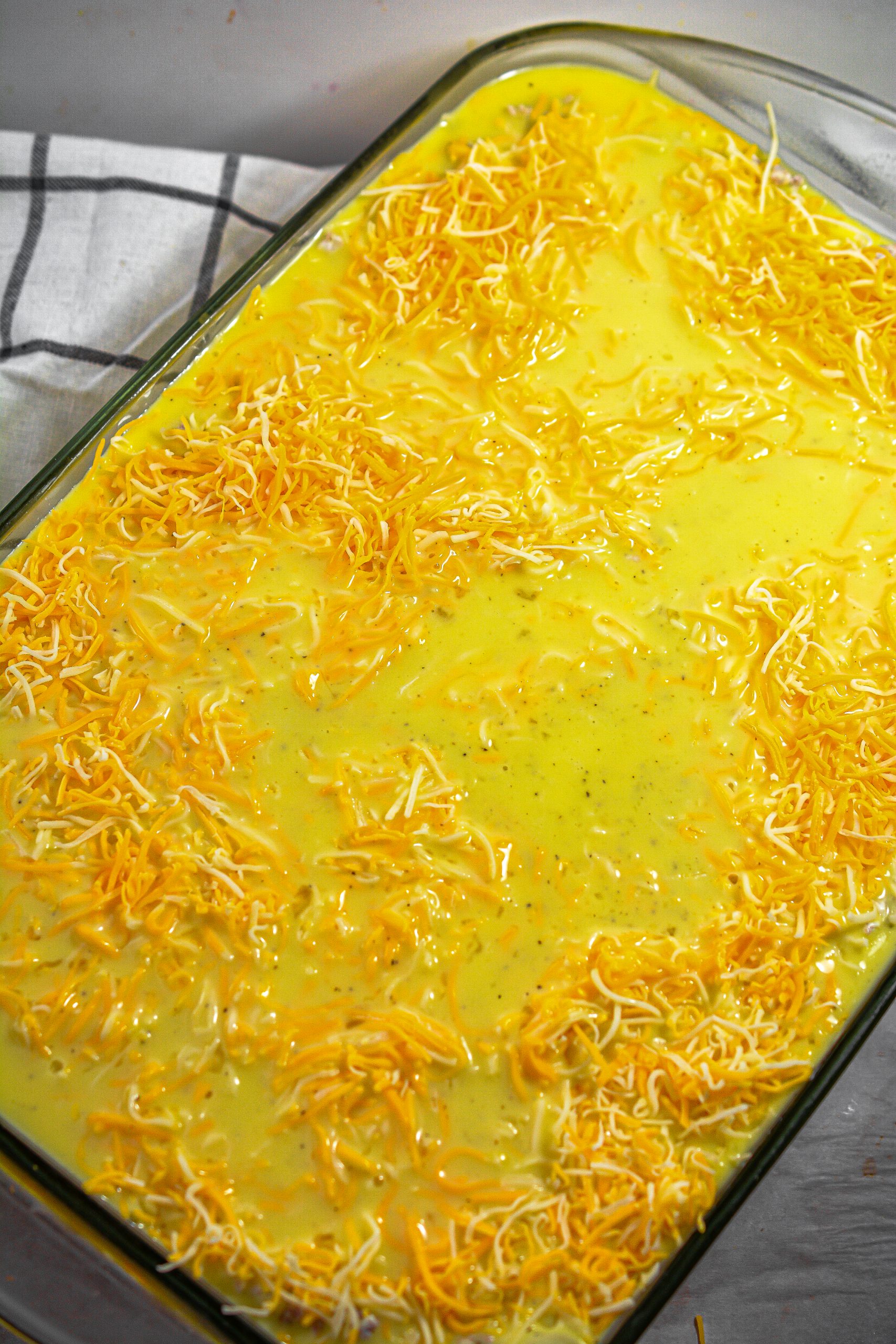 Pour the egg mixture over the cheese in the casserole dish.