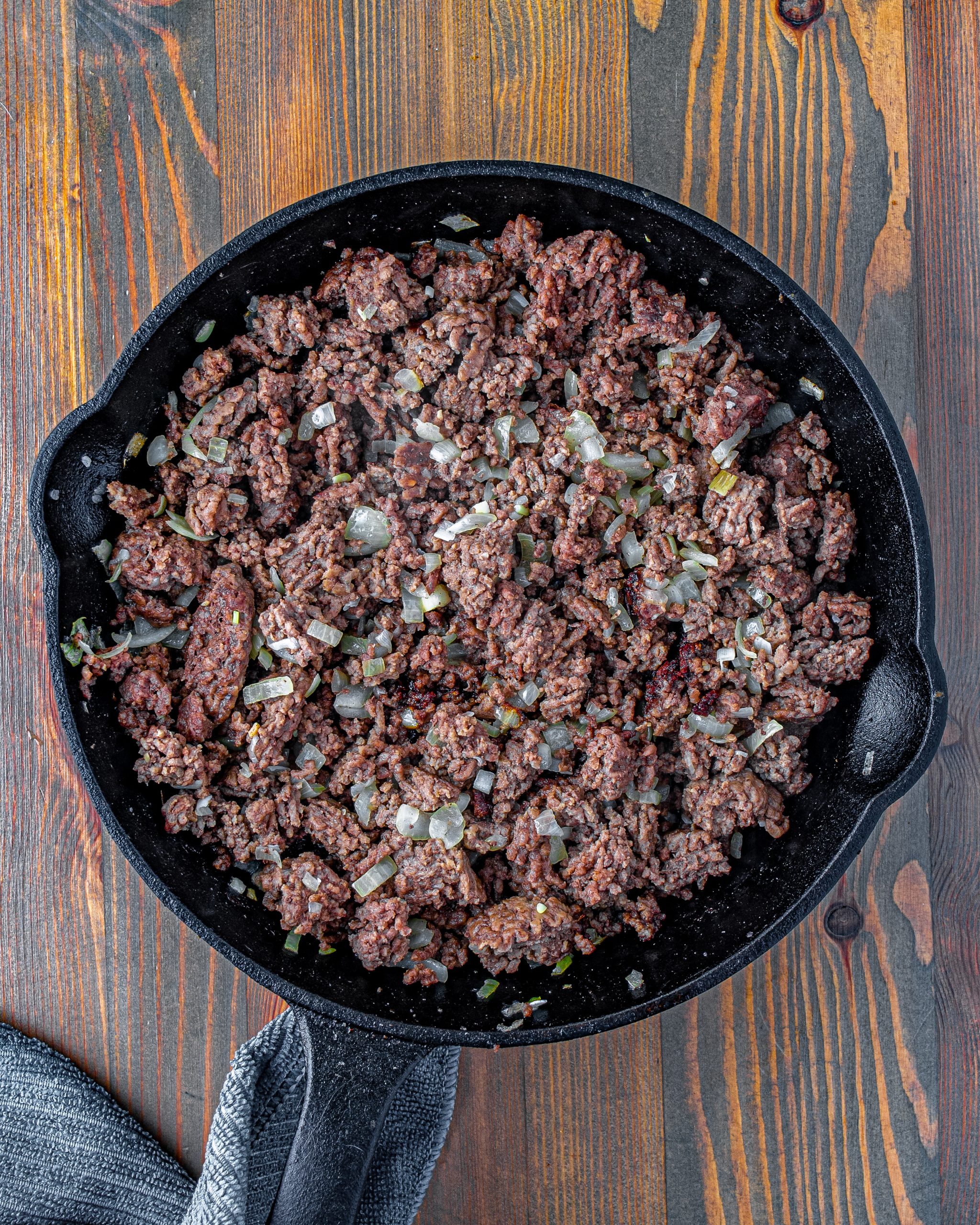 Place the ground beef and onion in an oven-safe skillet over medium-high heat on the stove. Saute until the meat is browned and the onions have softened.