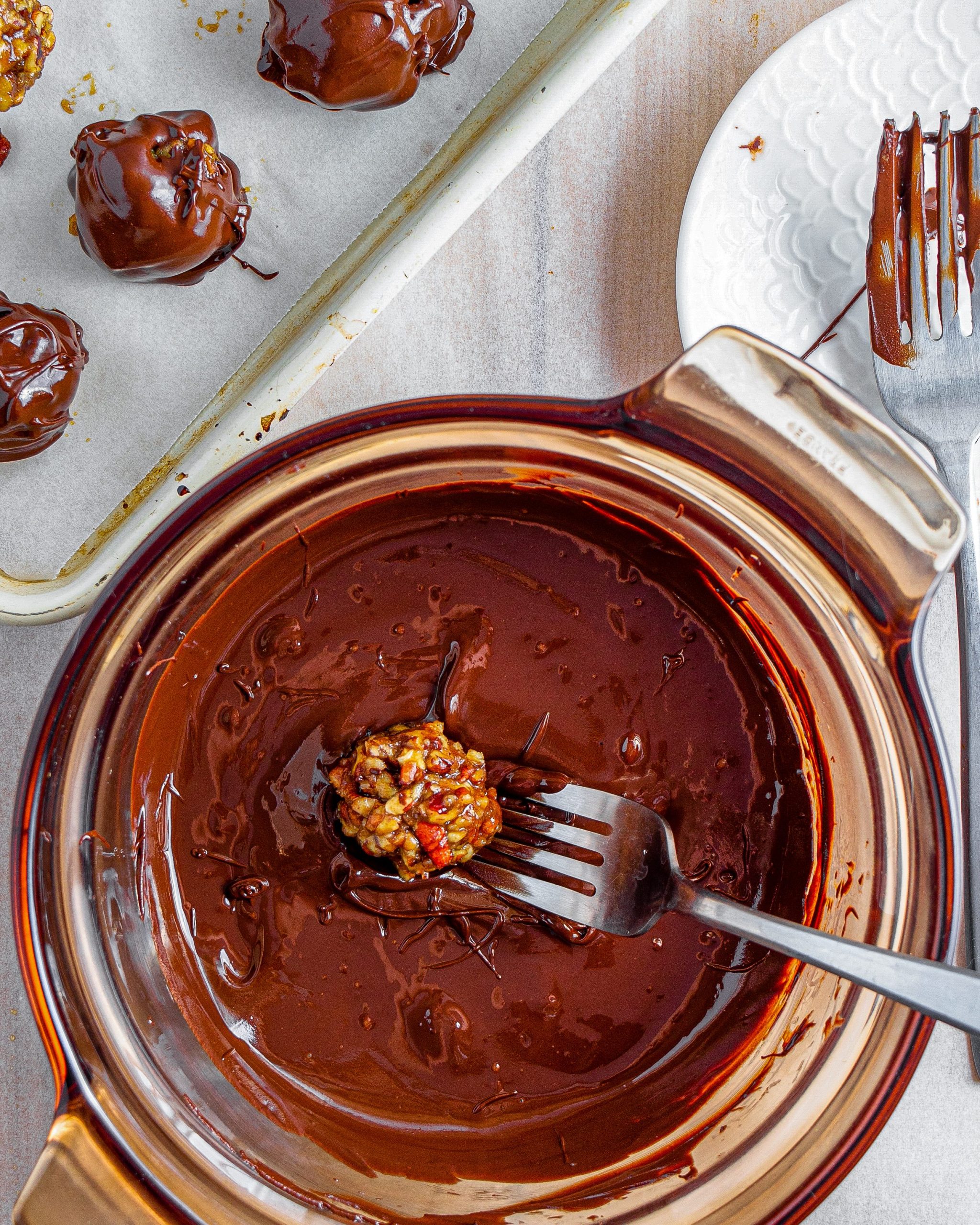 Dip the pecan pie balls into the chocolate, and return them to the parchment-lined baking sheet.