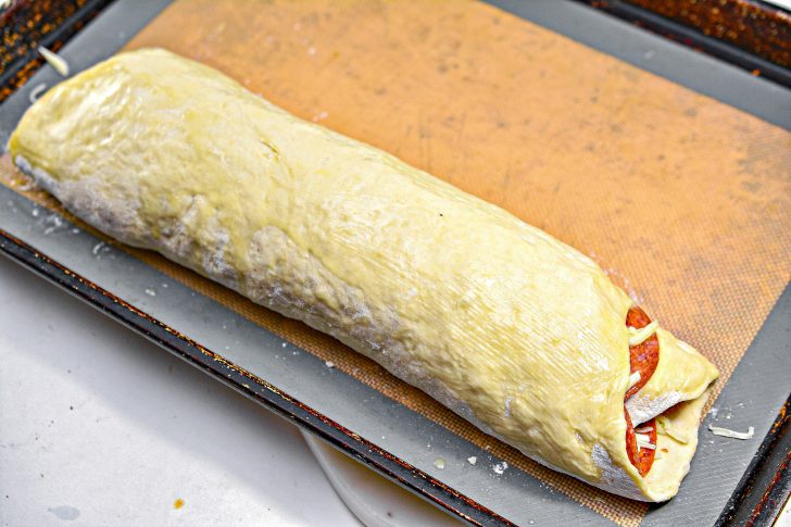 Starting at one end, roll the dough into a log with the cheese and pepperoni on the inside.