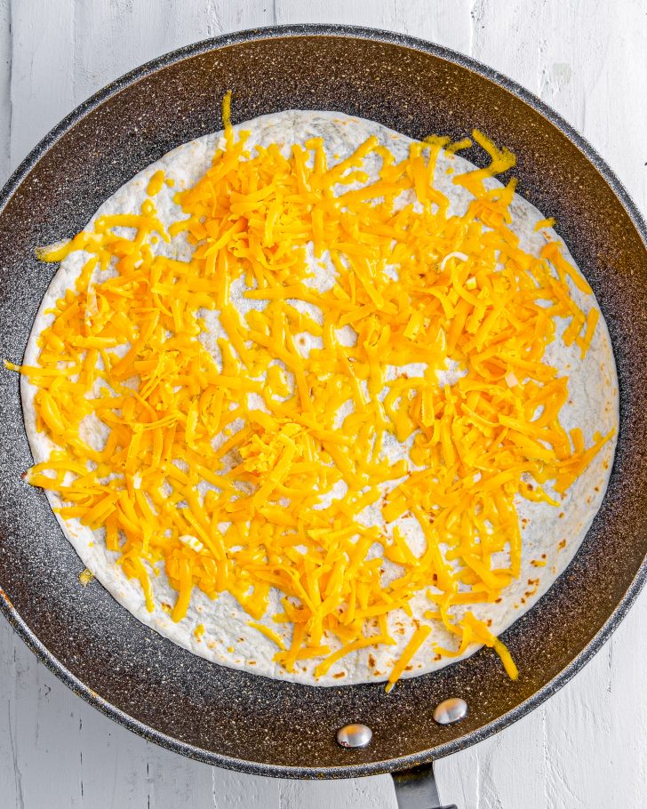 Place one large flour tortilla in the skillet and top with ½ cup of cheese.