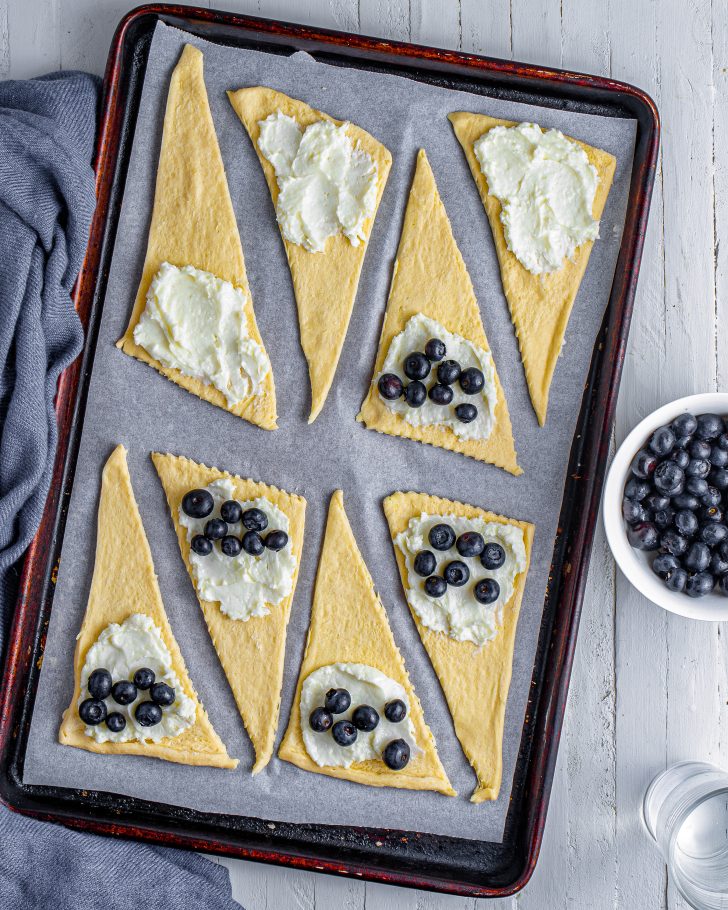 Add a teaspoon of the filling mixture to the wider end of each crescent roll along with some of the fresh blueberries. 