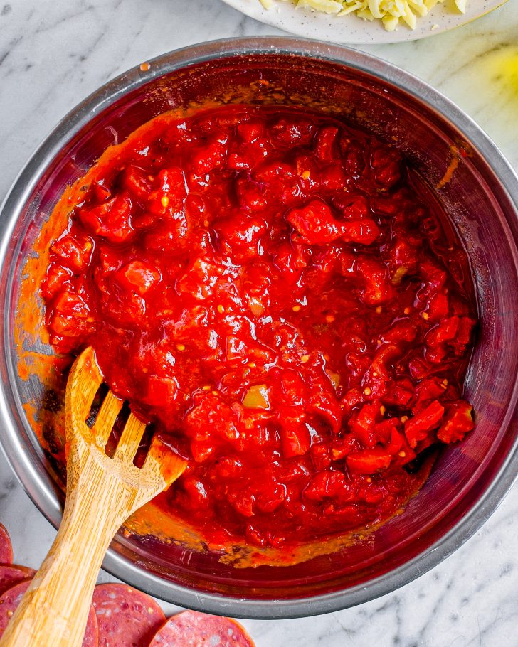 Using a small bowl, combine the pizza sauce and can of tomatoes.