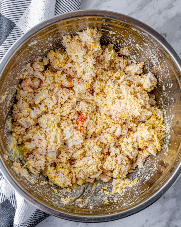 In a bowl, stir together the crab meat, paprika, mayonnaise, dijon mustard, onion powder, parmesan cheese, cracker crumbs, and salt and pepper to taste. 