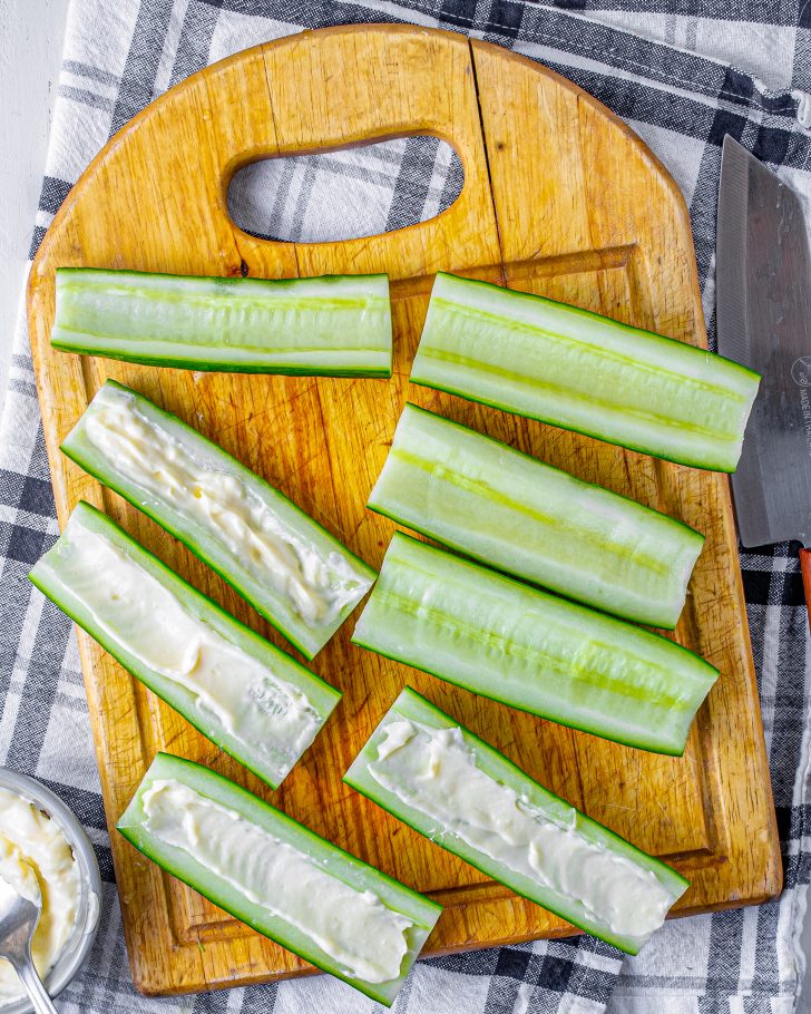 In one-half of the cucumber slices, spread a layer of mayonnaise or hummus, depending on what you have chosen to use. 