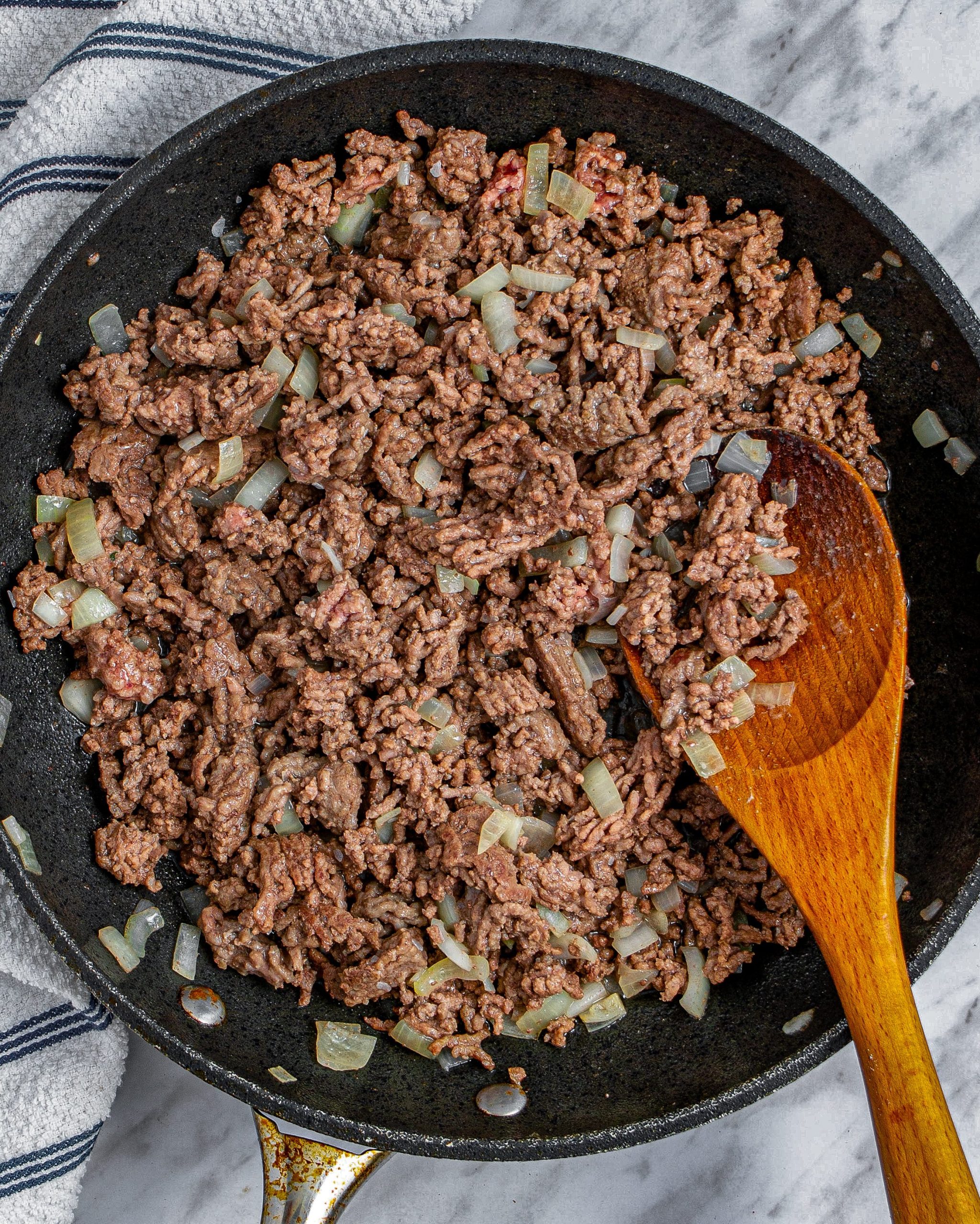 Add the ground beef and onion to the skillet and saute until the meat is completely browned and the onion has softened.