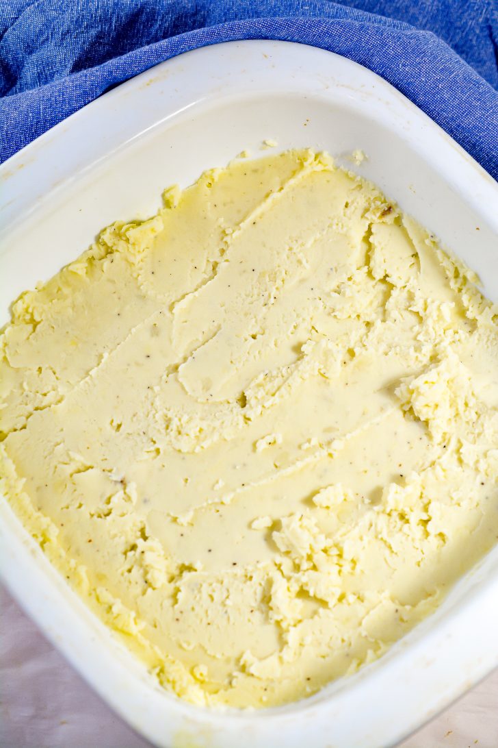 Layer the mashed potatoes on the bottom of a well-greased 9x9 baking dish.