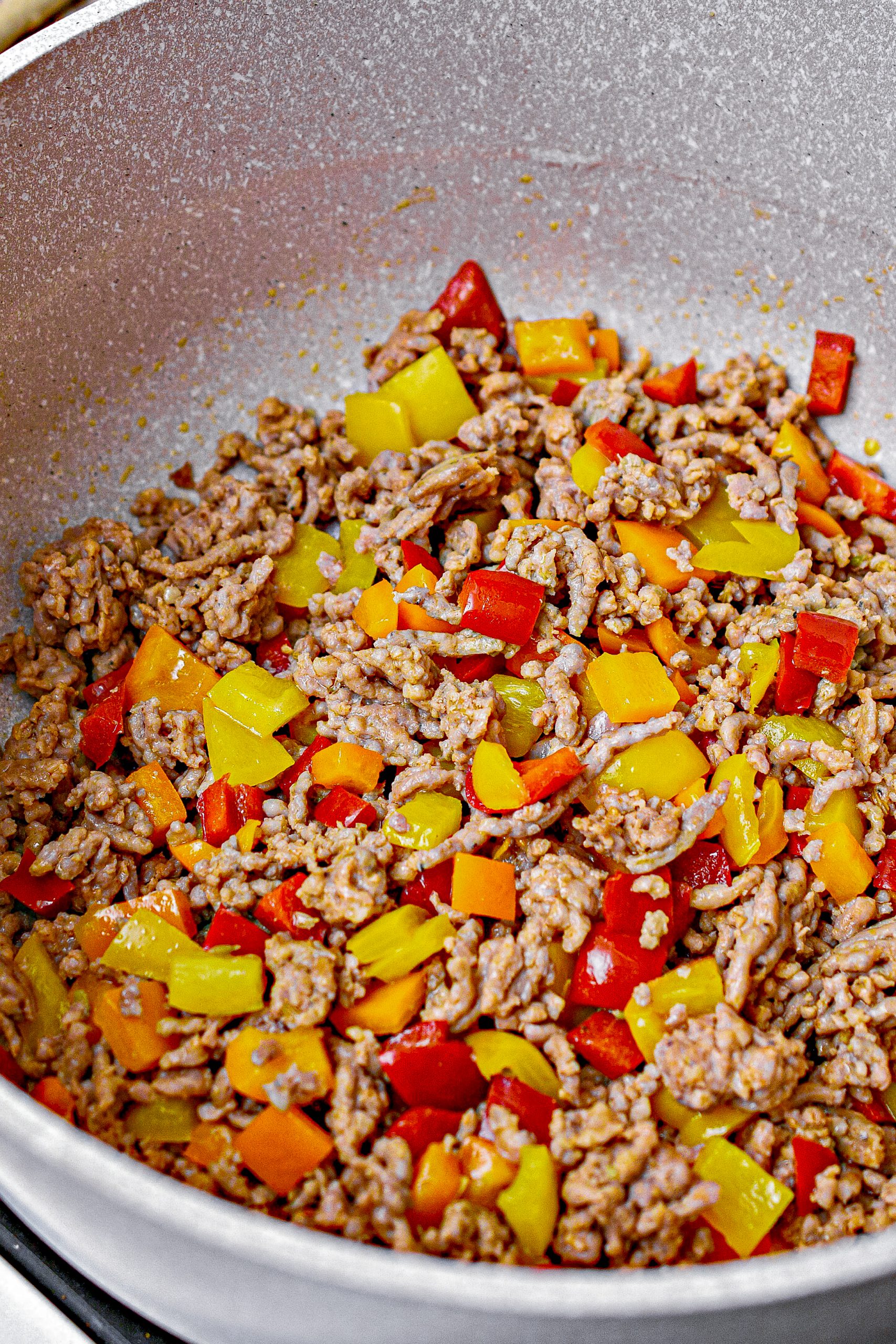 Add the meat and peppers to a large saucepan or skillet with deep sides over medium-high heat. Cook until the meat is completely browned and the peppers have begun to soften.