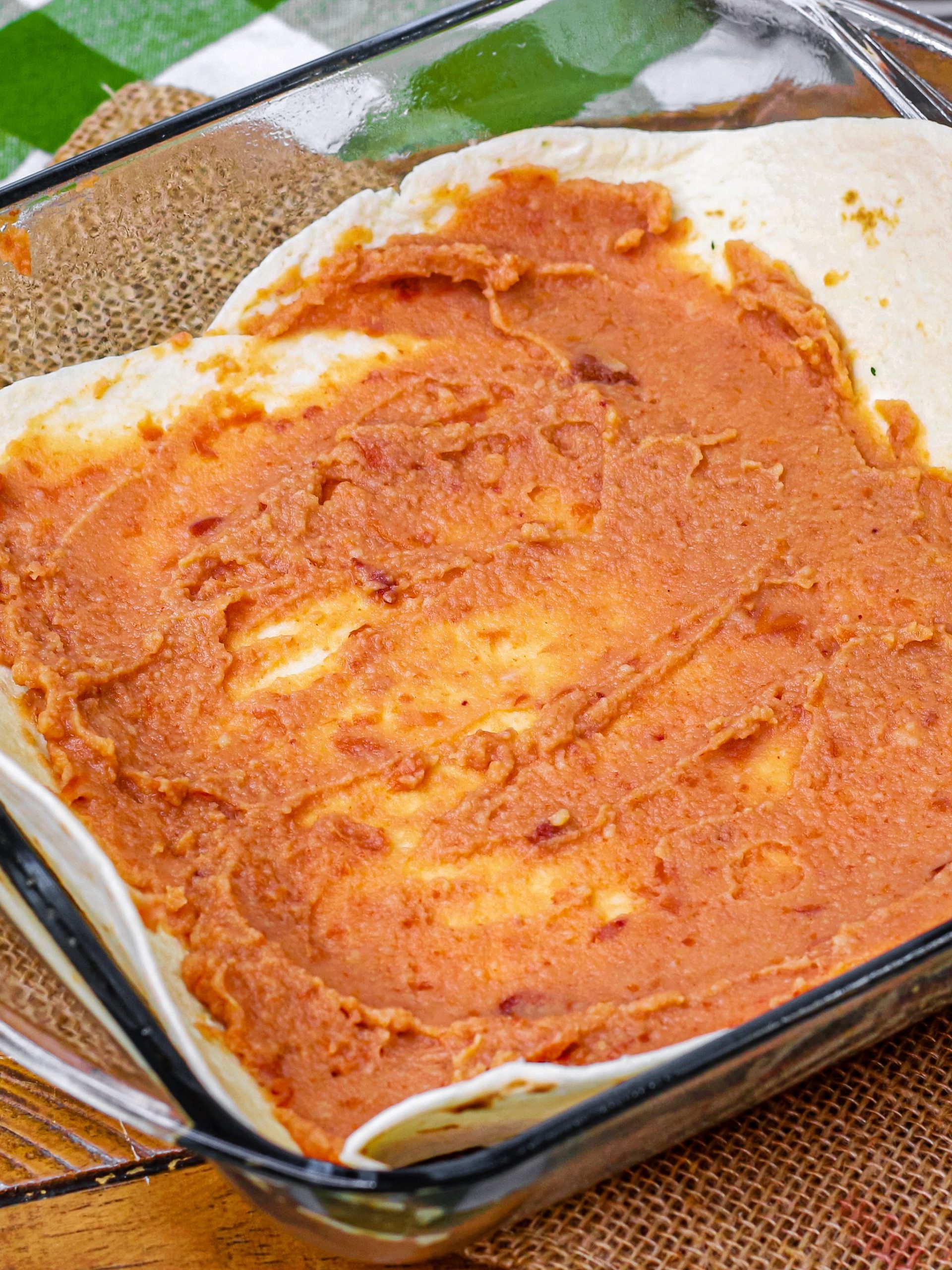 Spread 1/3 of the refried beans on it, 1/3 of the meat, and ⅓ of the cheddar cheese.