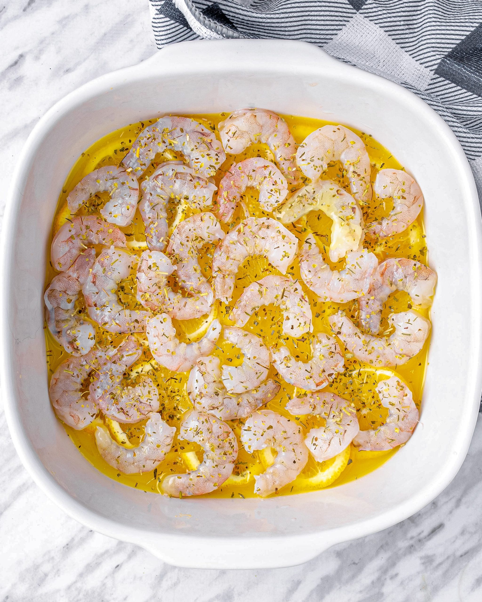 Arrange the cleaned and deveined shrimp on top of the lemon slices.