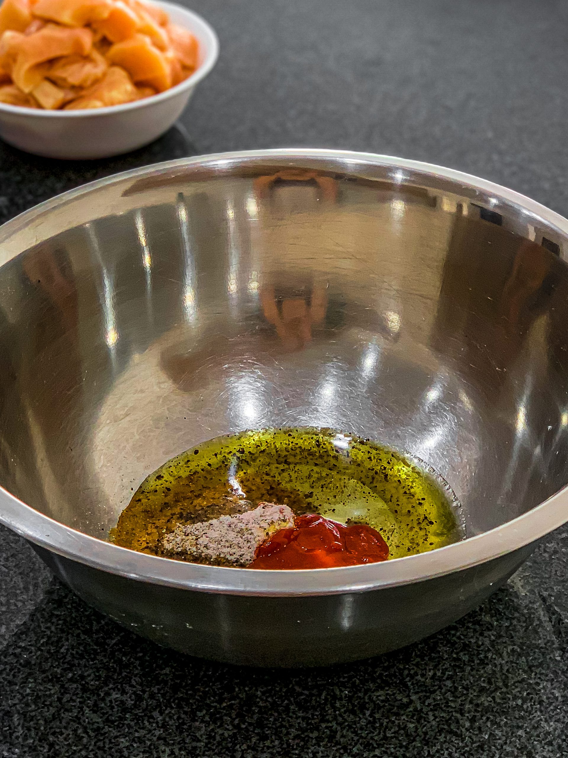 In a large bowl, mix together paprika, salt, pepper, garlic powder, olive oil, and hot sauce.