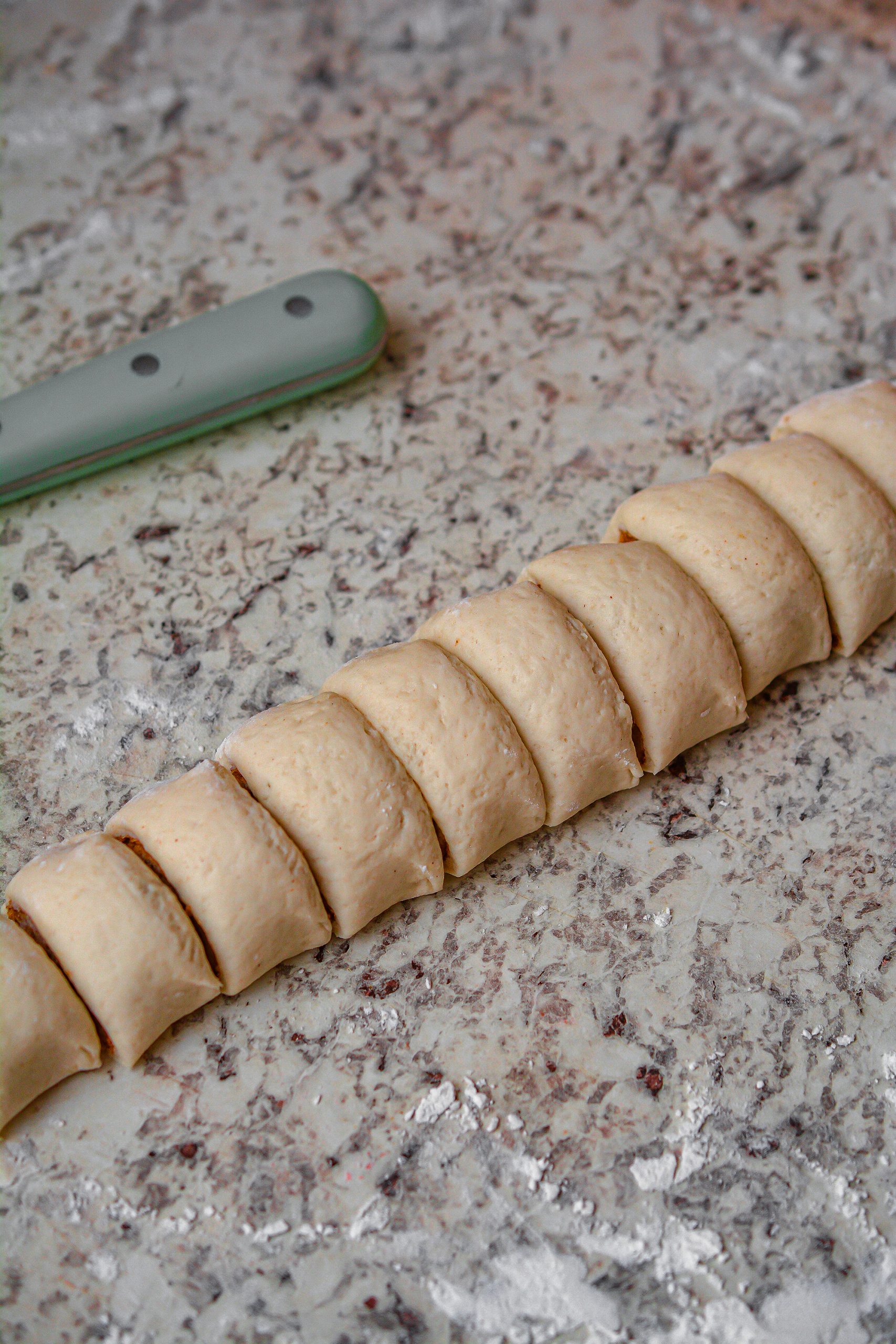 Cut the ends off of each log of dough, and then slice each log into 12 even pieces.