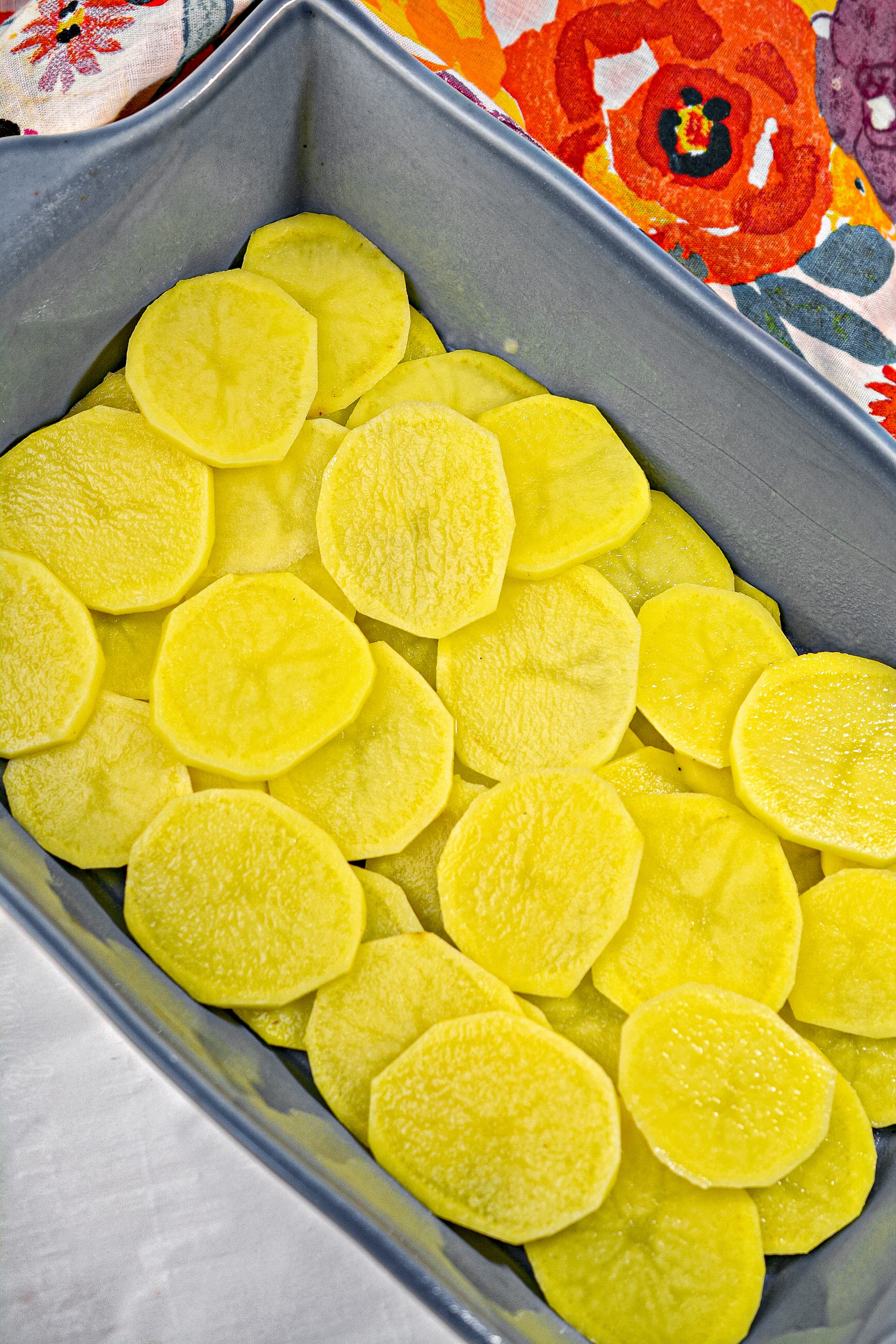 Layer the sliced potatoes on the bottom of a 9x13 baking dish.