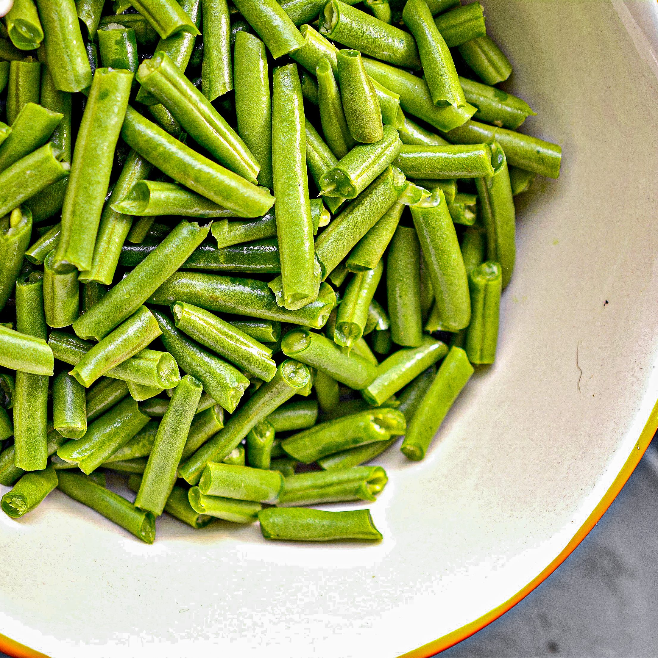 Start by adding 2 lbs of fresh green beans snapped and cut into pieces into a slow cooker.