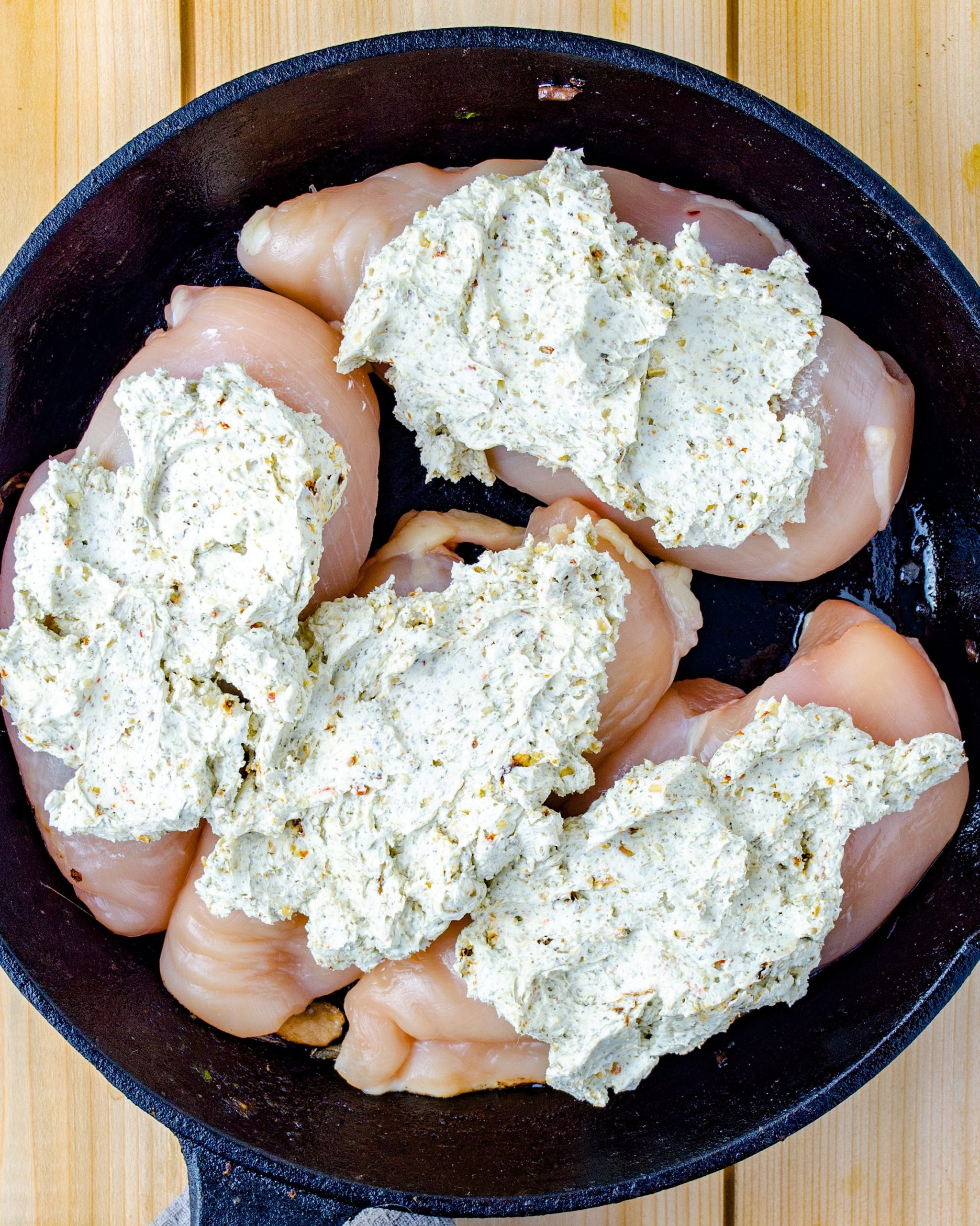 Place the chicken breasts into a well-greased baking dish, and top each one with an equal portion of the cream cheese mixture. 