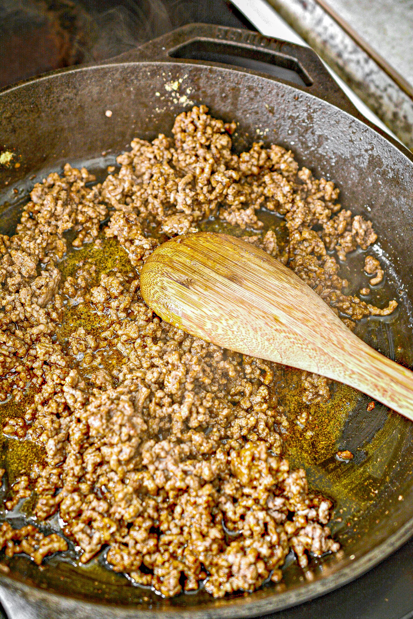 Cook the ground beef in a skillet over medium-high heat until it is completely browned.