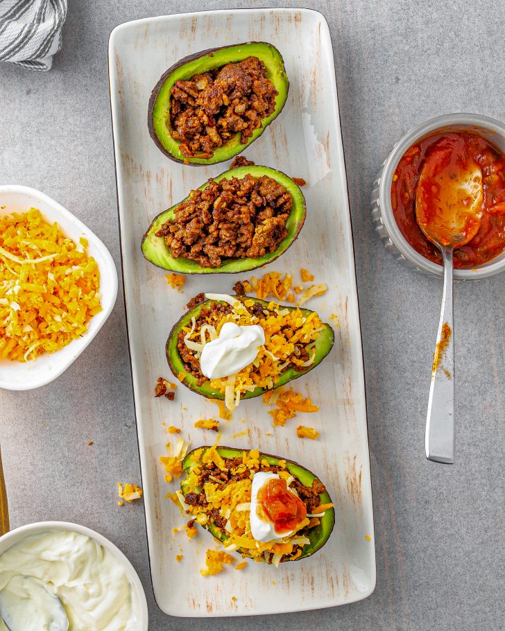 Fill the avocado shells with the taco meat and top with shredded cheese, sour cream, and salsa.