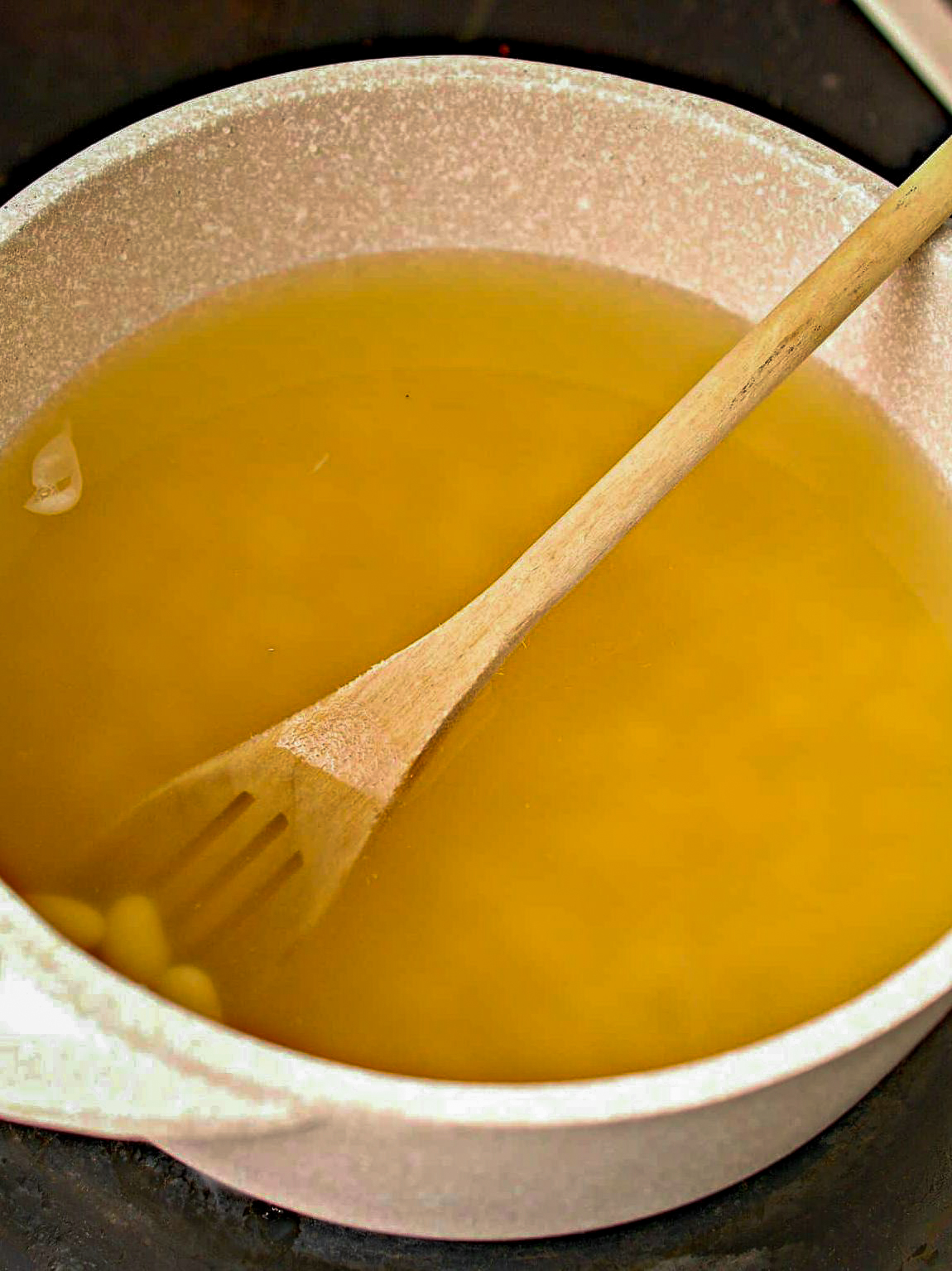 In a pot over medium-high heat on the stove, bring the chicken broth and can of beans to a boil.