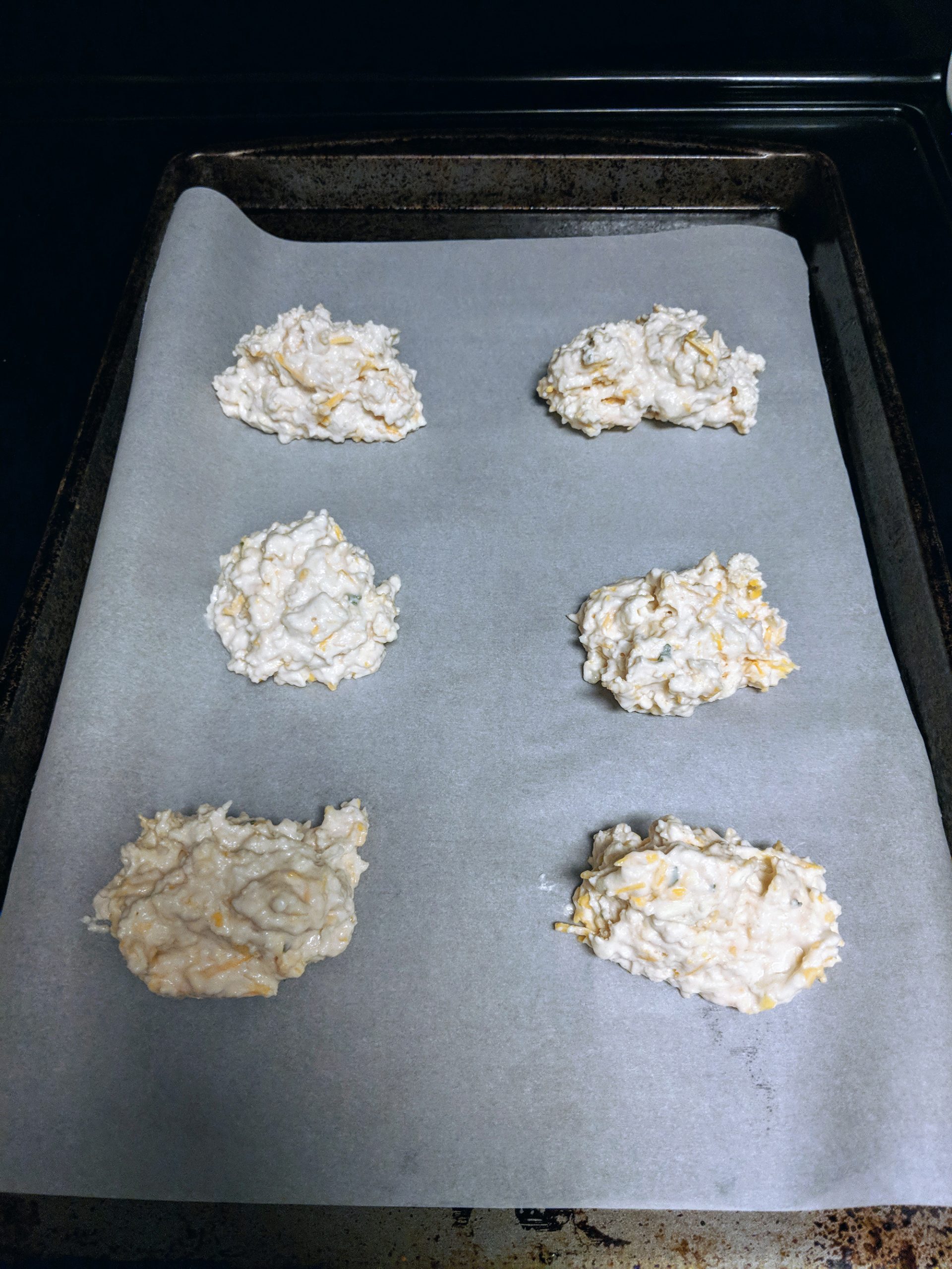 Cheesy garlic biscuits on baking sheet