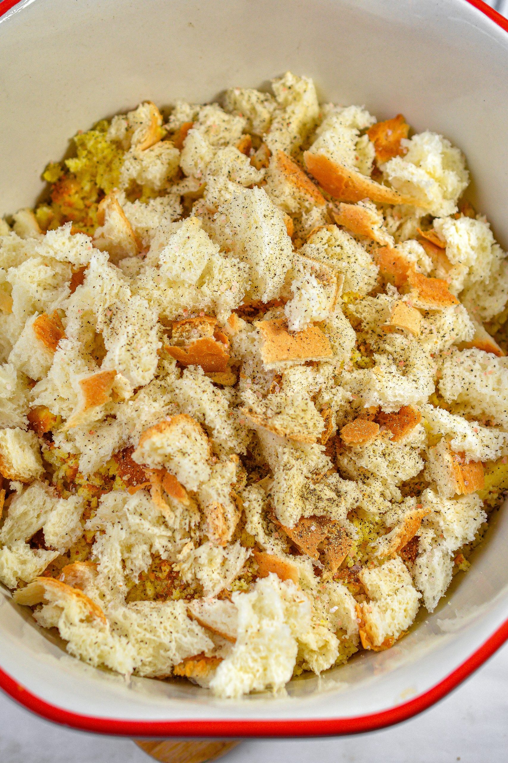 Crumble the cornbread, and place it into a large mixing bowl with the three slices of bread that have been torn into small pieces.