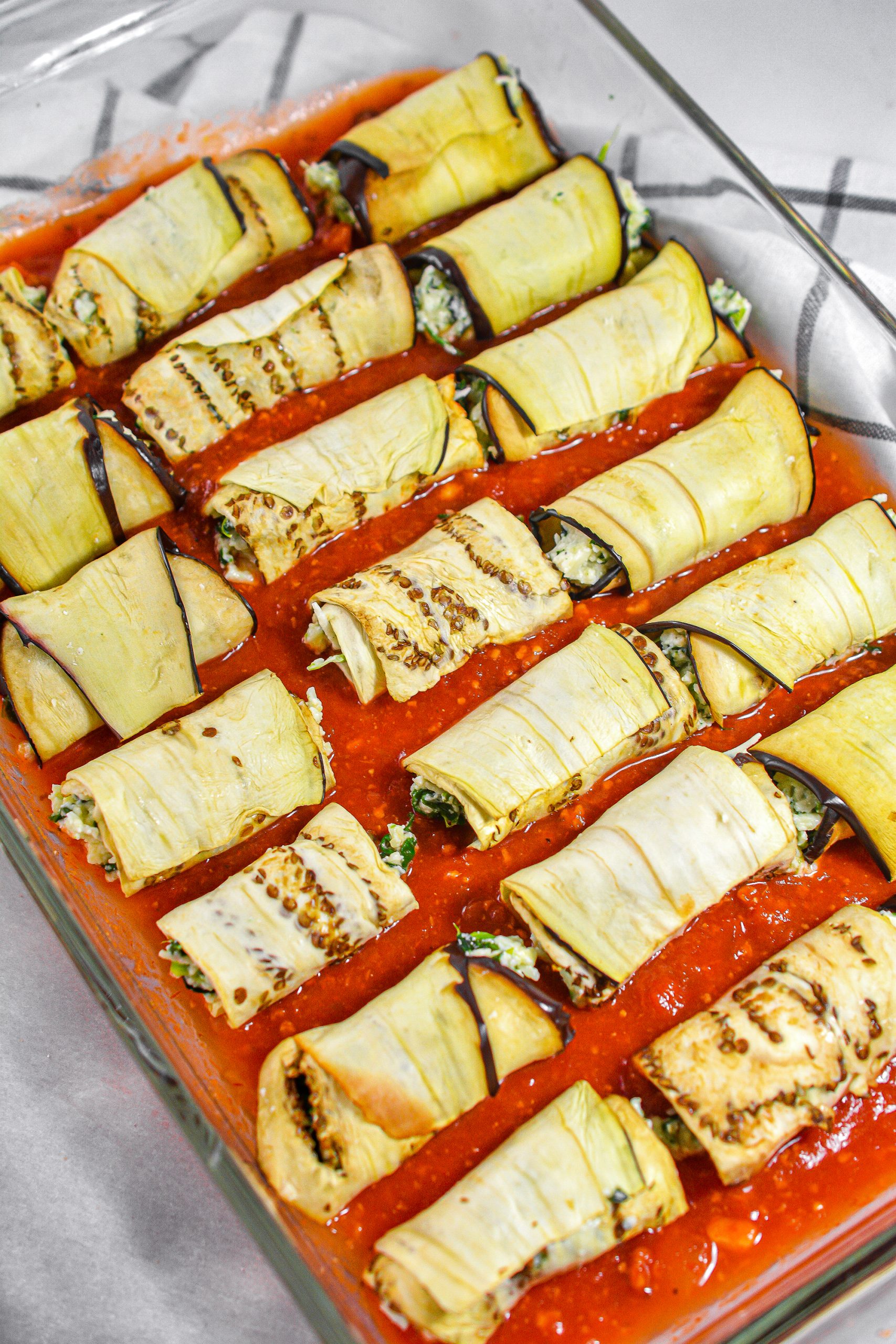 Place the filled eggplant rolls into the baking sheet on top of the sauce.