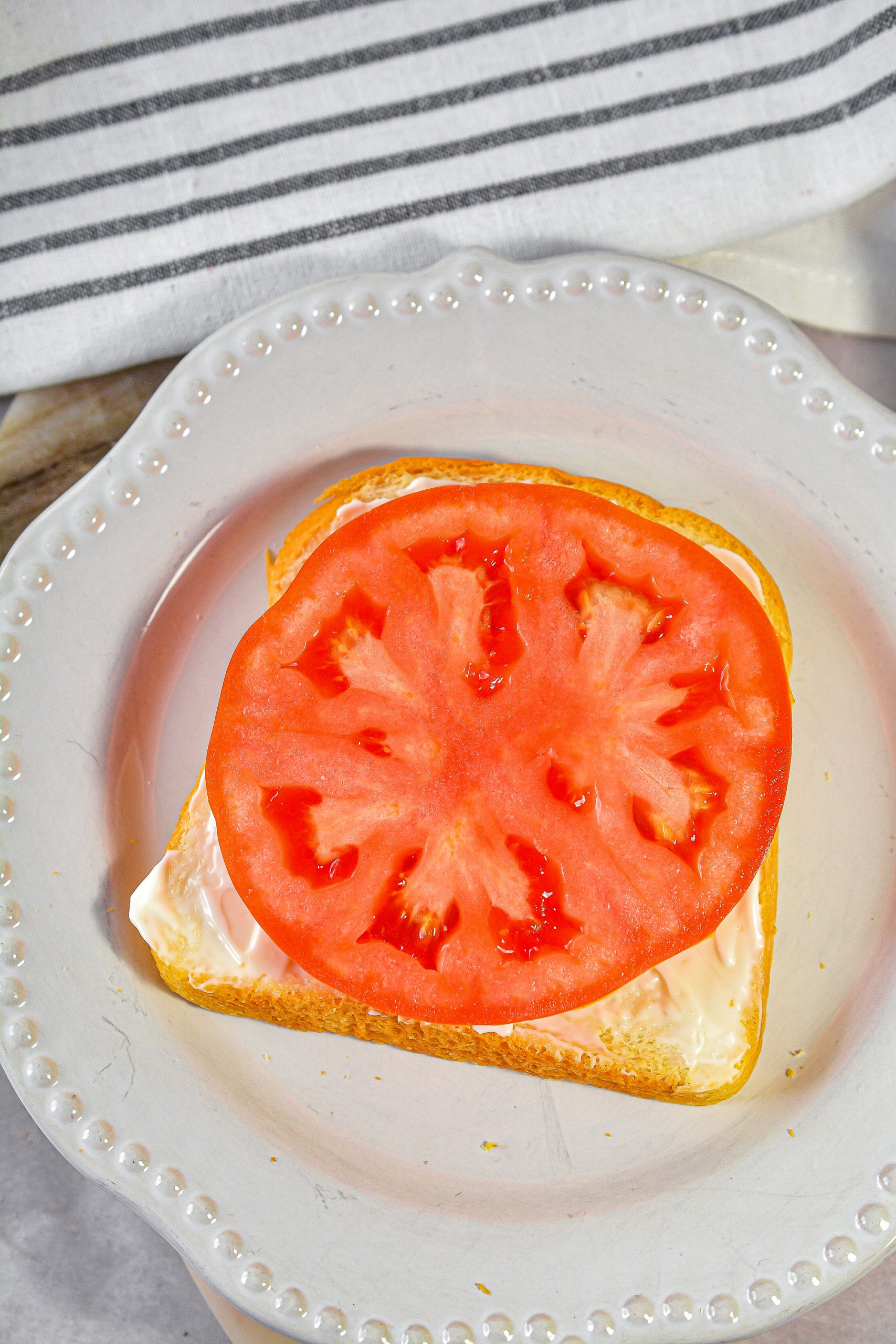 Place a slice of tomato on top of the slices of bread with the mayo.