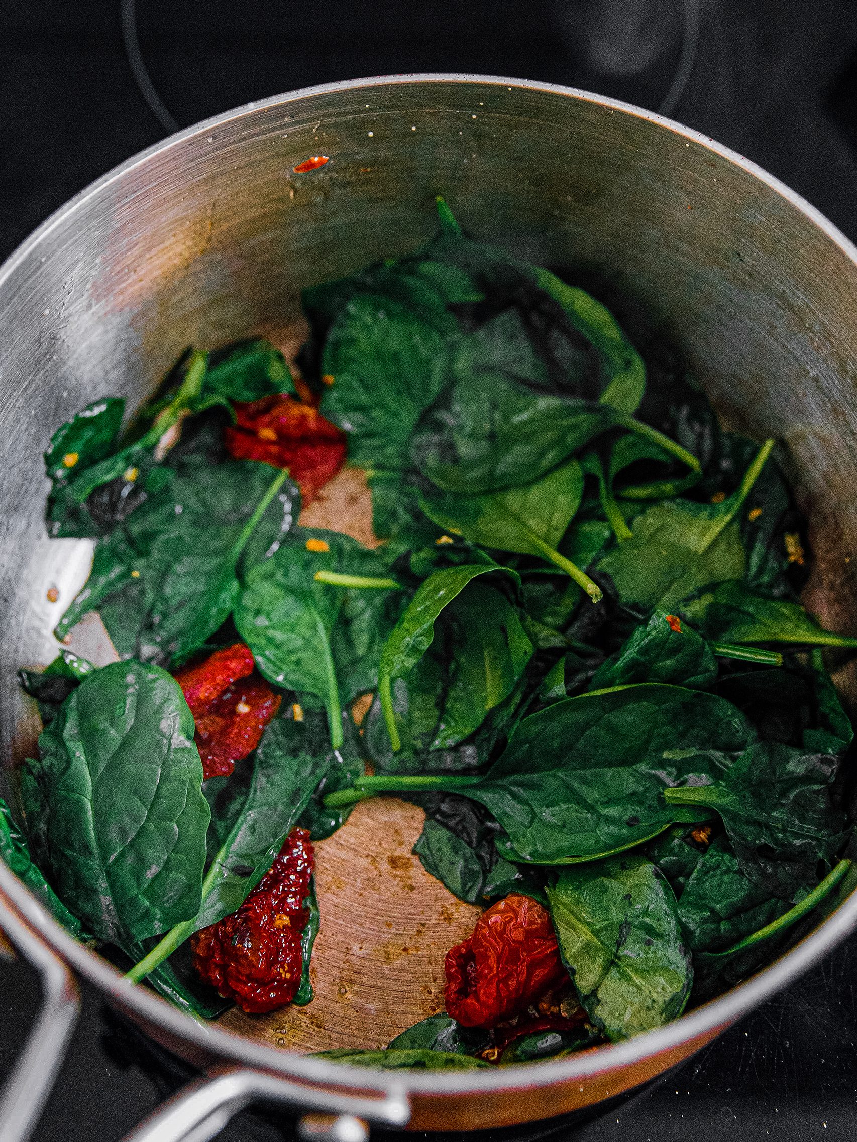 In a saucepan over medium heat melt butter and add in the tomatoes, garlic, and spinach. 