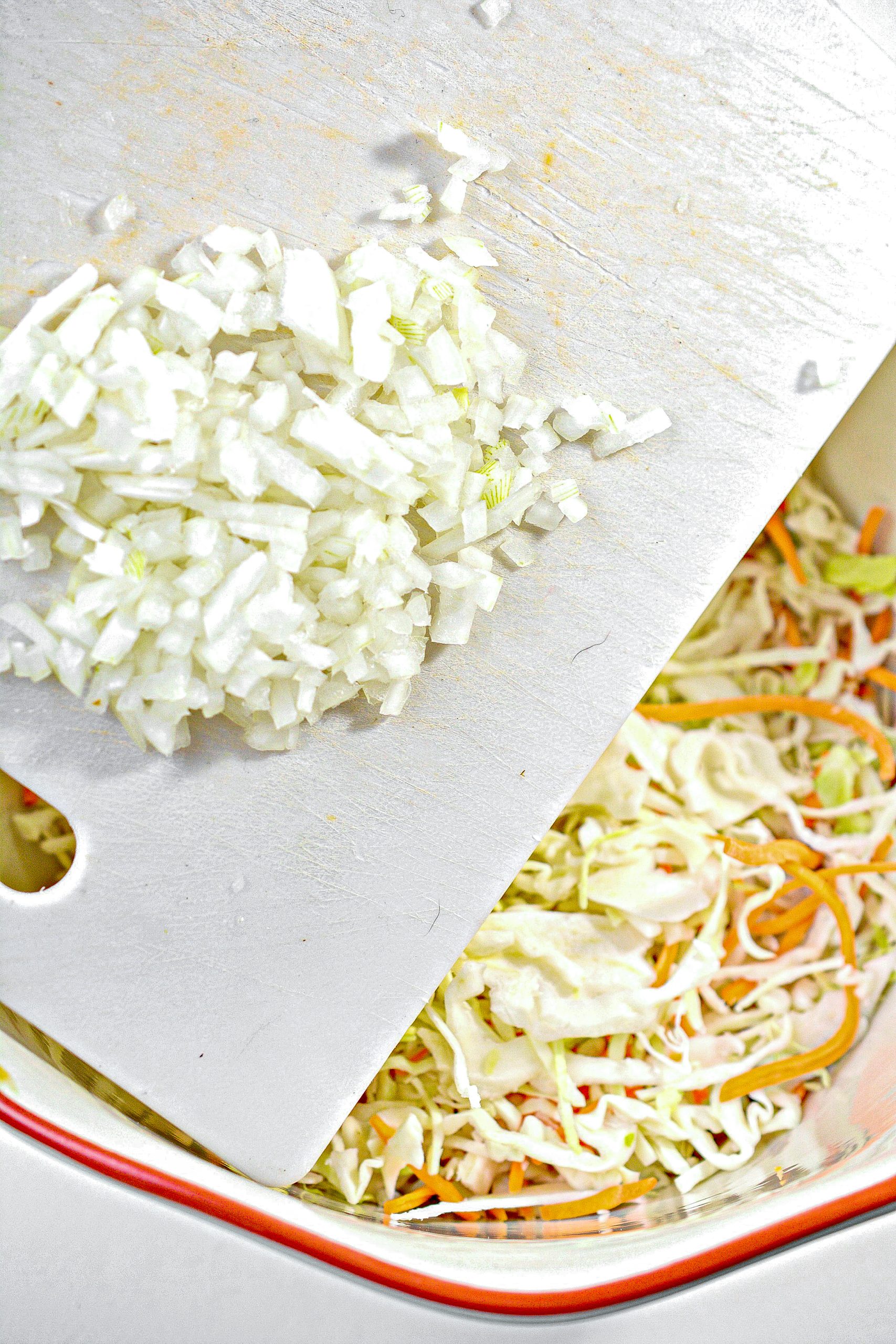 Place the cabbage, onions and carrots into a large mixing bowl, and mix to combine well.
