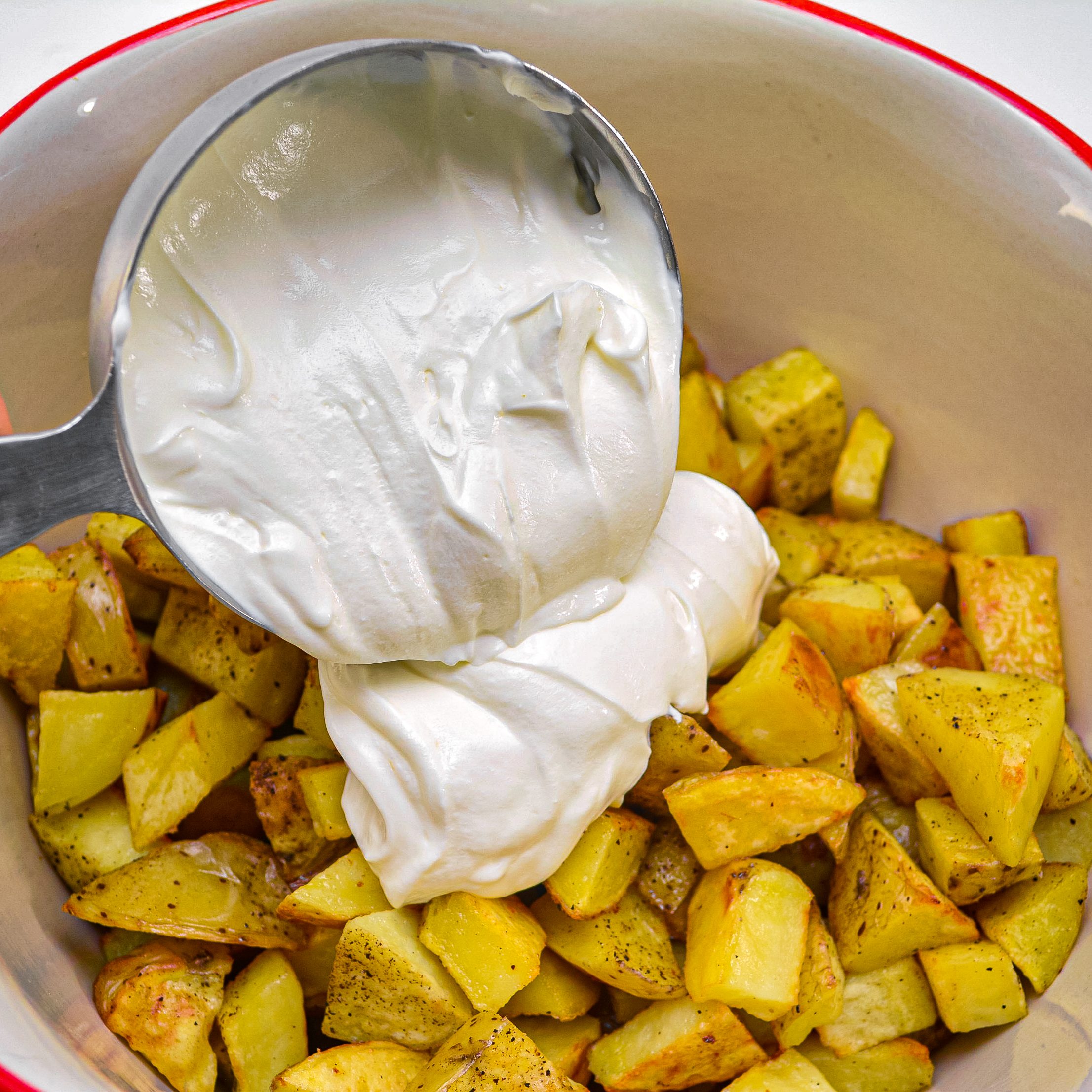 Place the cooled potatoes in a large mixing bowl, and add 1 ½ cups of sour cream. Stir carefully to combine well.