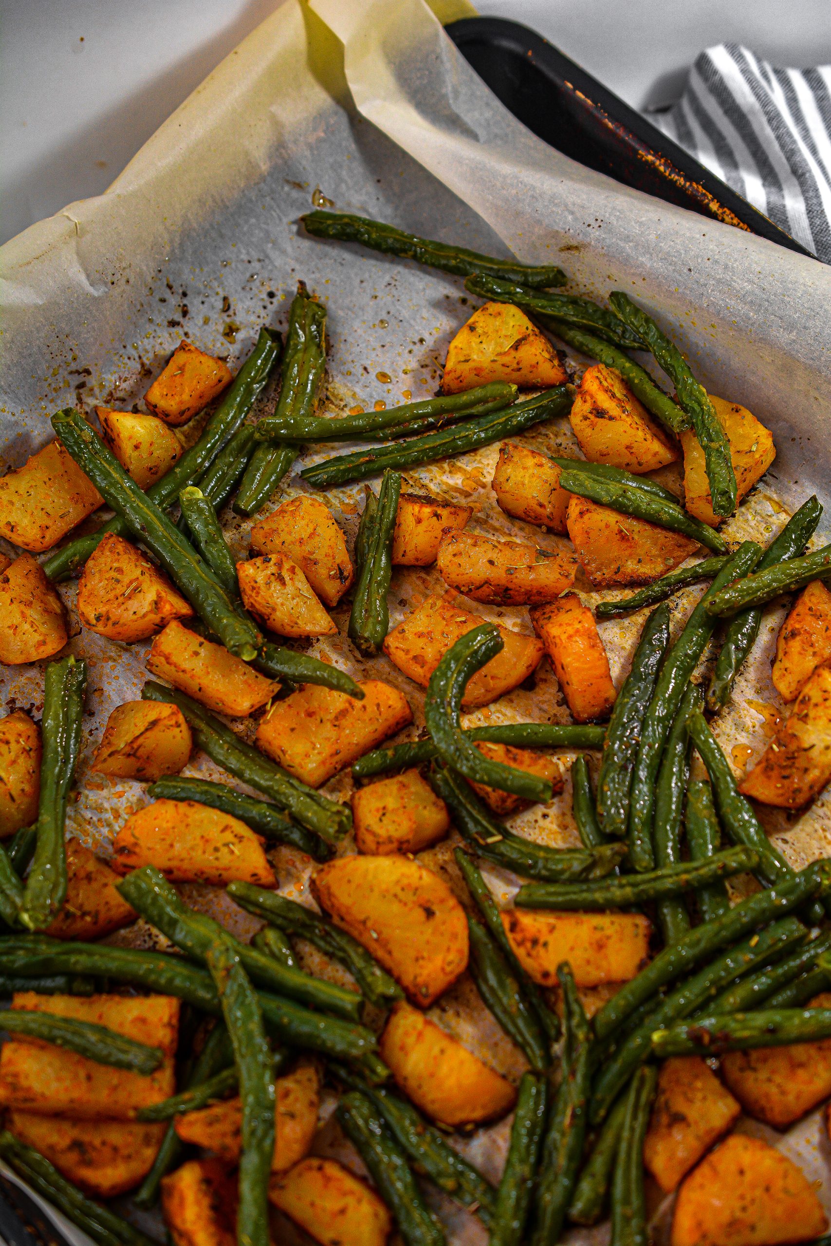 After 15 minutes, remove the potatoes from the oven and add the green beans to the tray.
