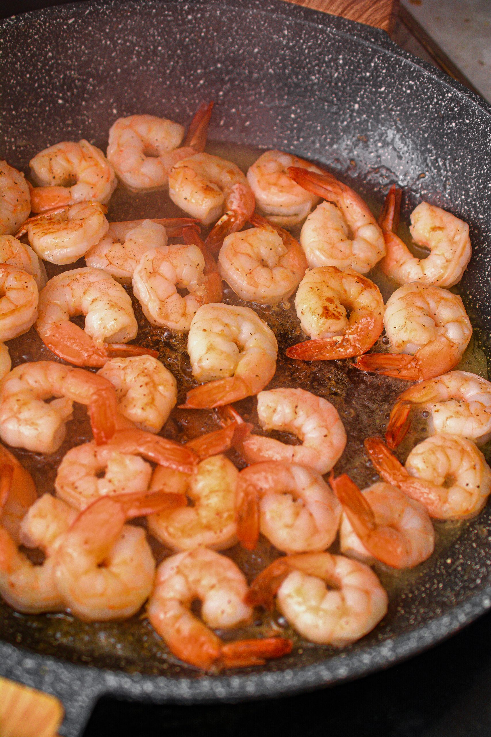 Season the shrimp with salt and pepper to taste, and add to a skillet over medium high heat